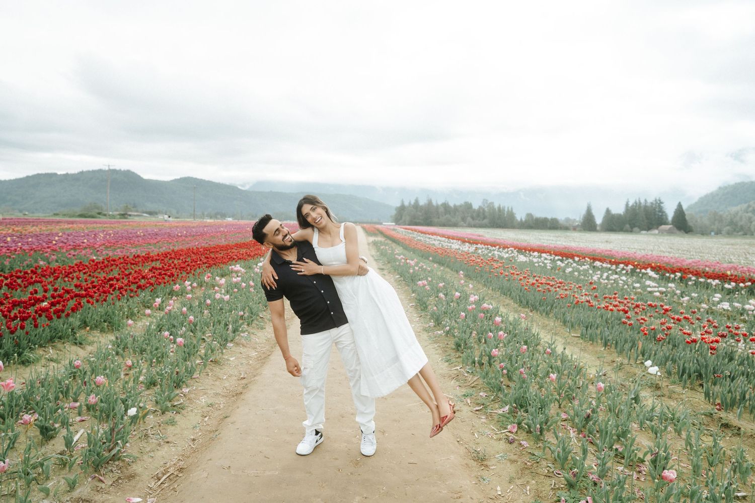 A couple strolls through vibrant red tulip fields in Washington State during spring bloom season.