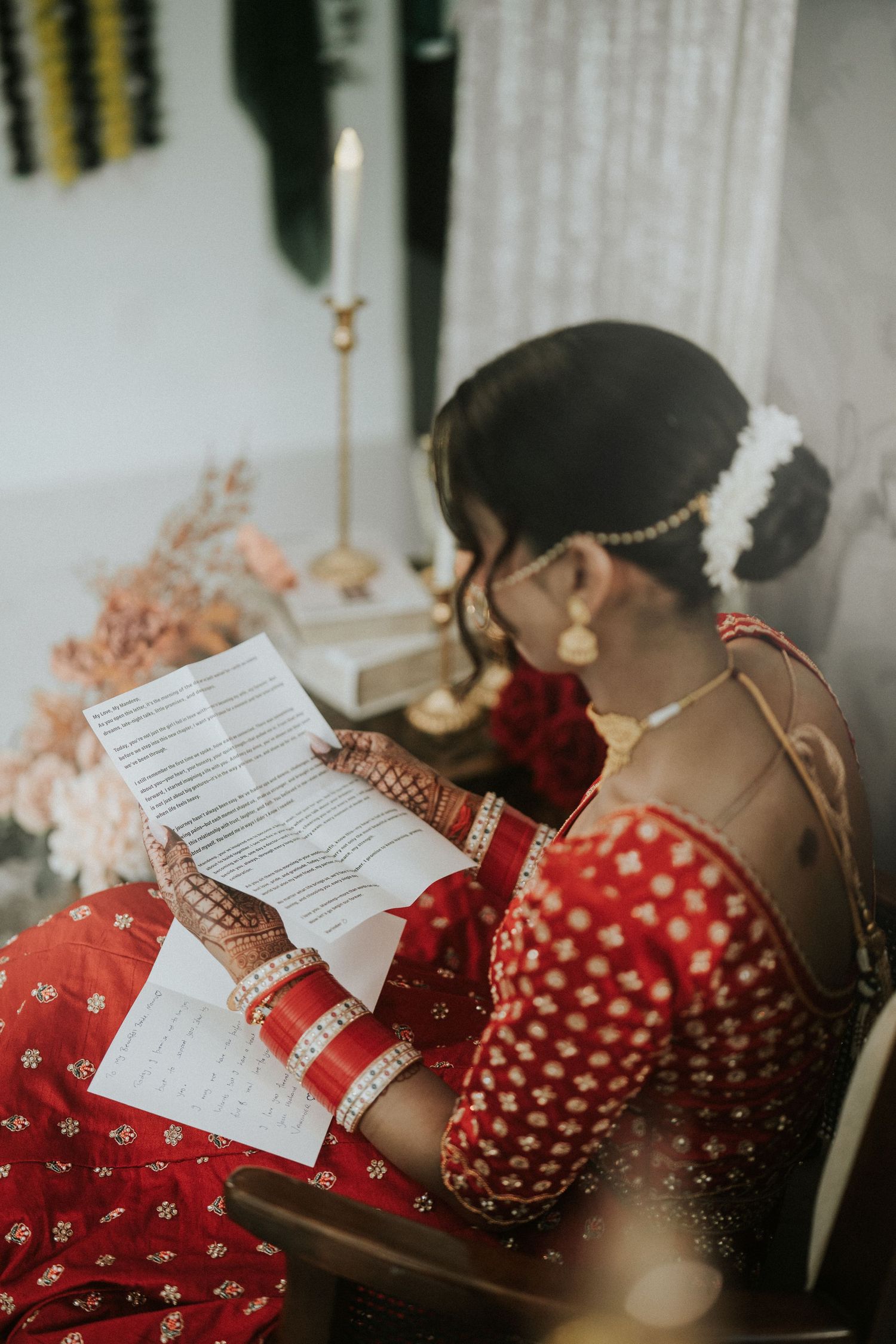 Detail shot of bride in red wedding attire reading traditional ceremony documents.