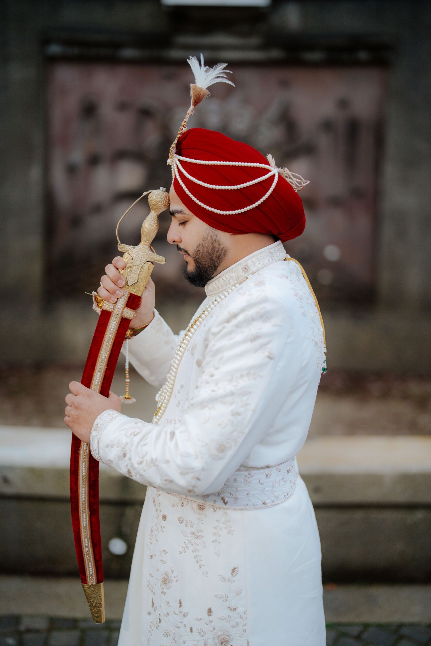 Side profile shots of groom holding ceremonial sword in traditional white wedding attire.