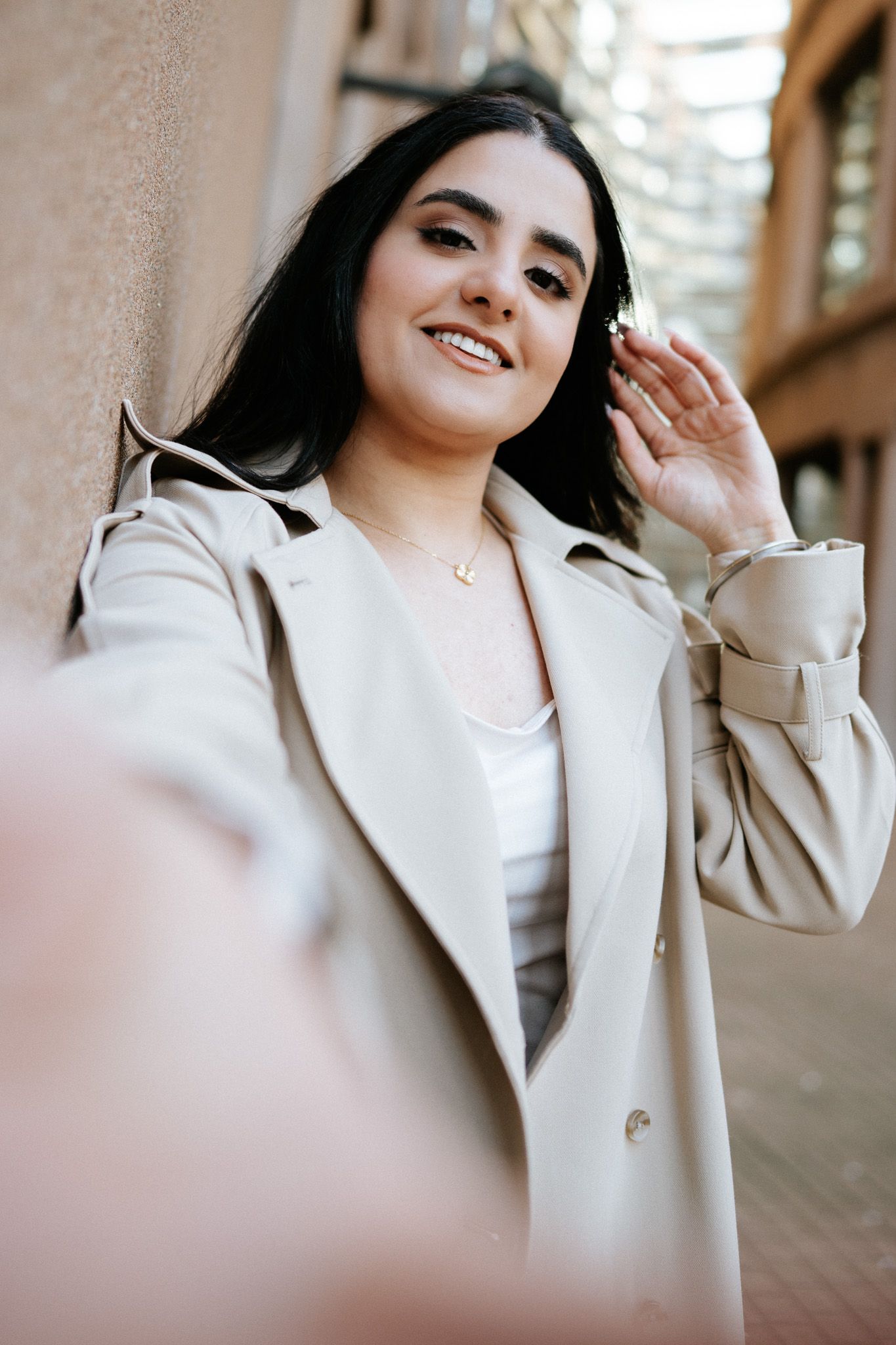 A person wearing a cream colored blazer poses and smiles in a series of connected lifestyle portraits.