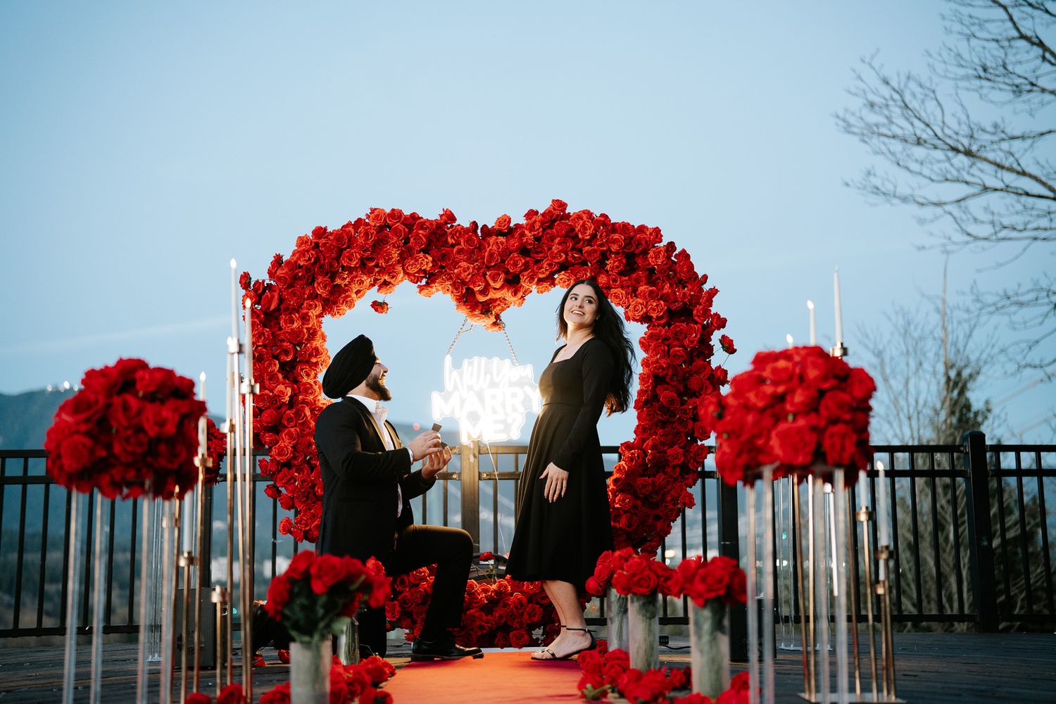 A vibrant red art installation with flowing fabric creates an arch against a winter sky and bare trees.