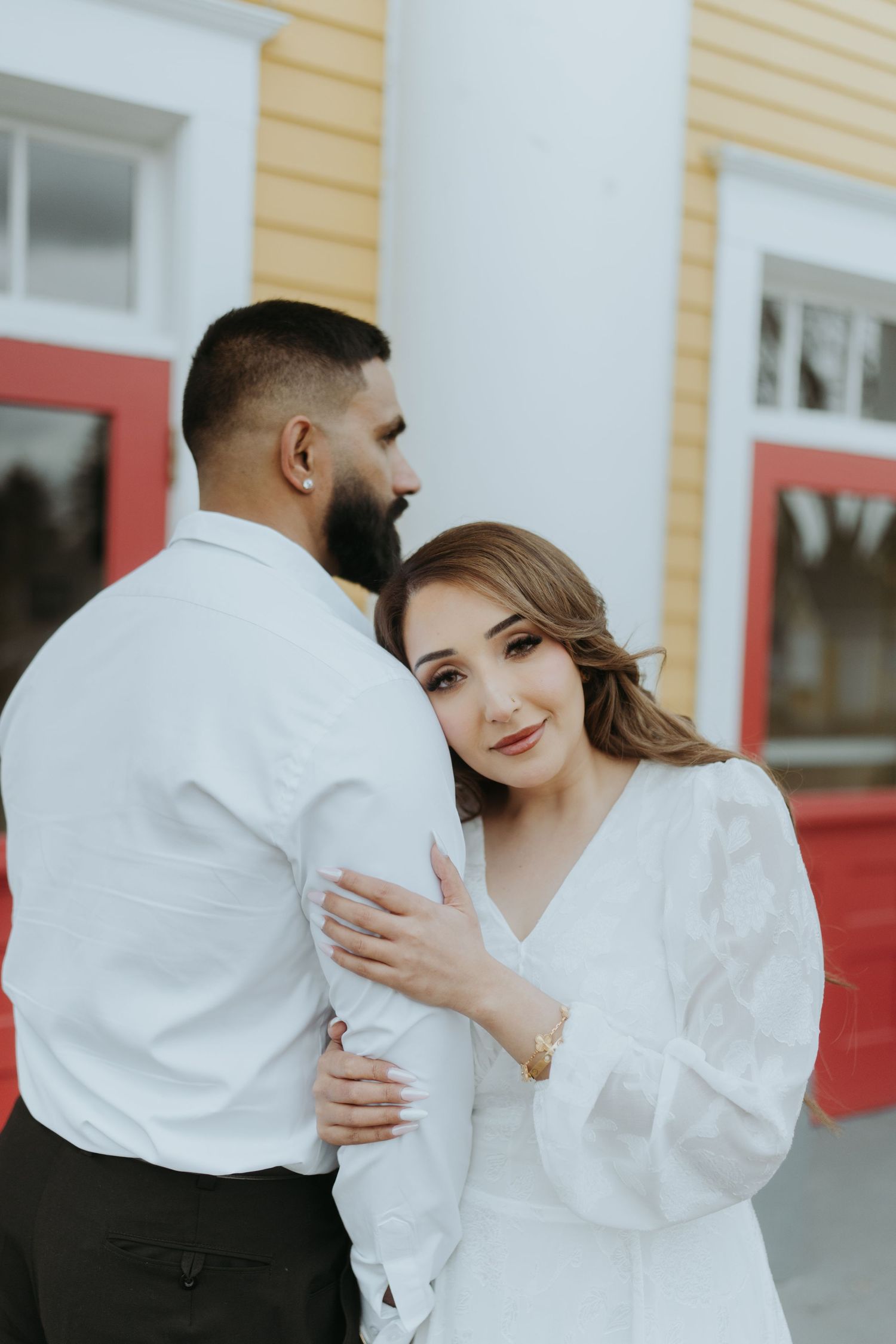 Couple in white clothing share emotional moments during their photoshoot.