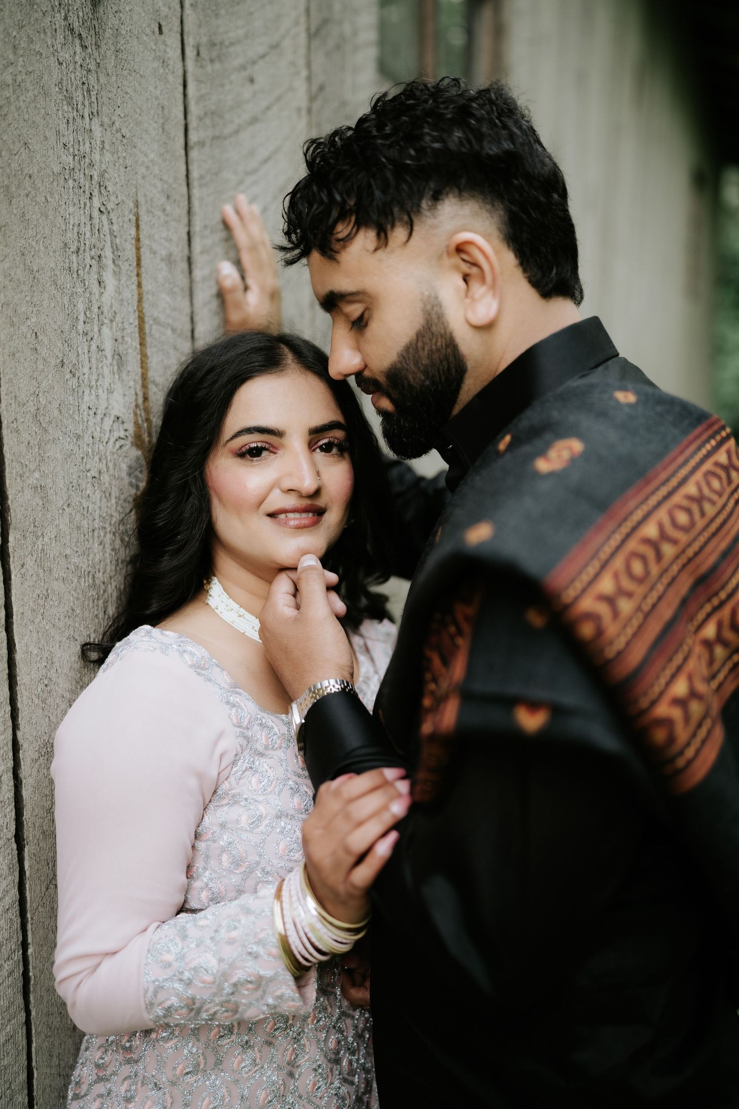 A couple shares tender moments against a concrete wall in a series of intimate portraits.