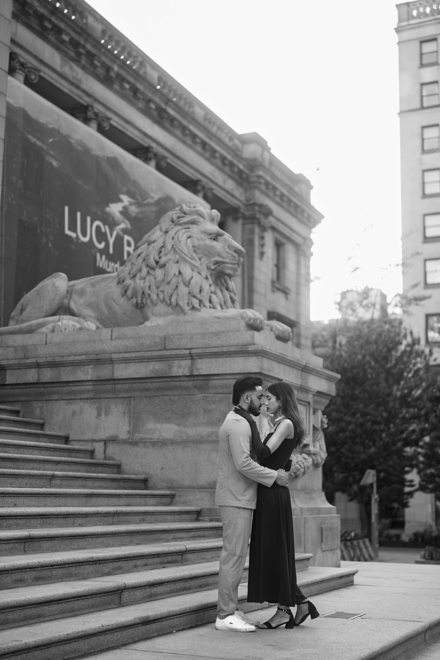 A romantic couple sits on stone steps outside a historic building in a vintage black and white photograph.