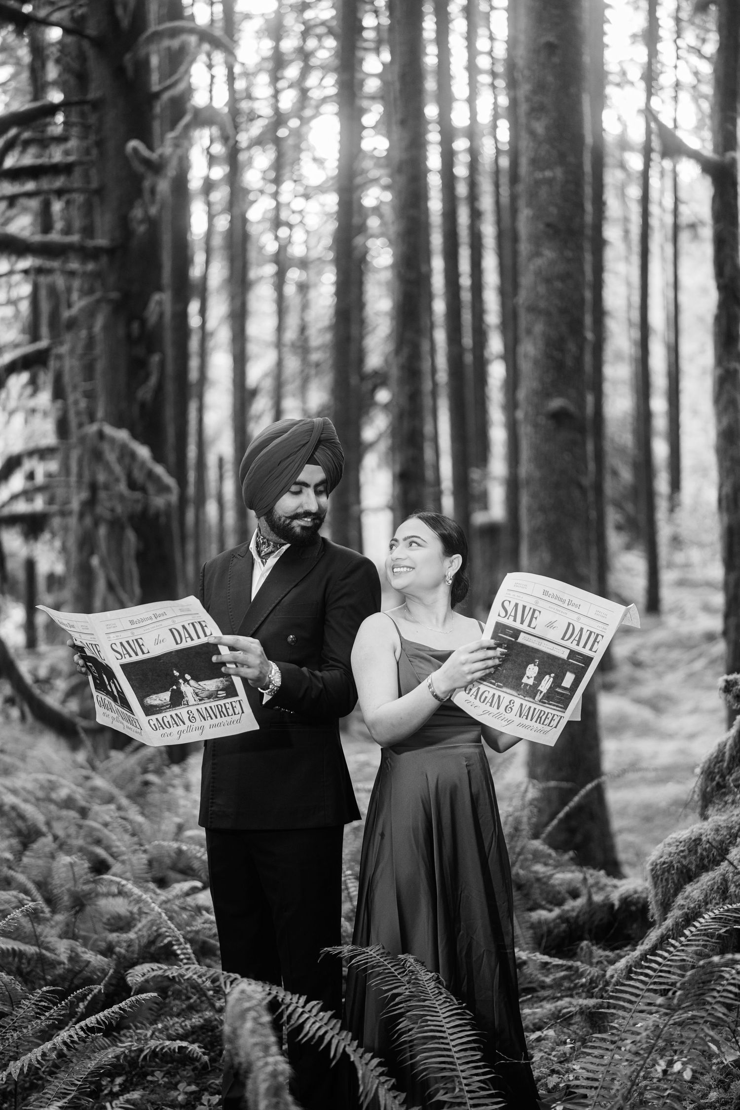 Artistic black and white engagement photos with couple holding newspapers in forest.