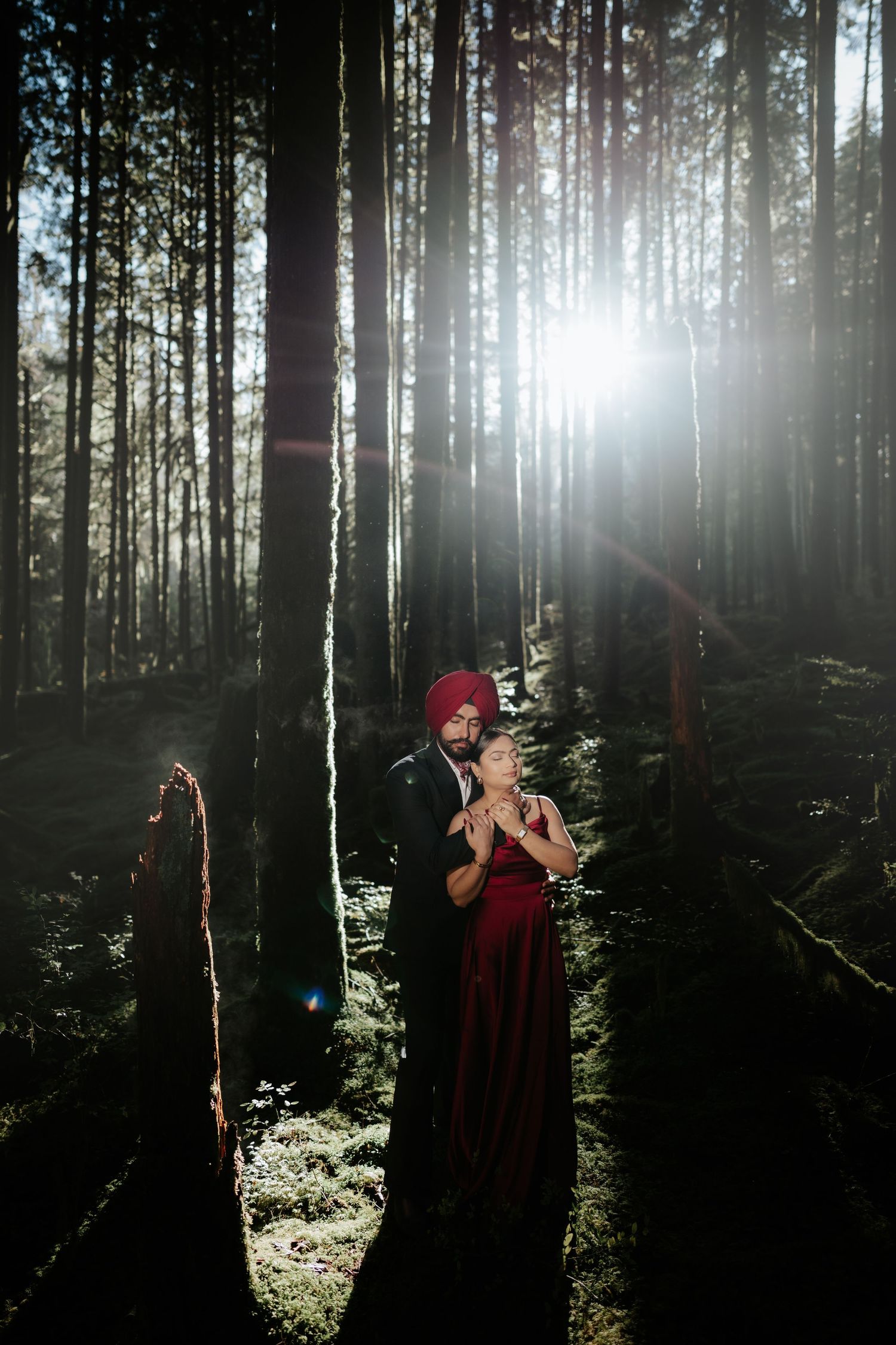 Moody forest photography session with red accents against dark tree silhouettes.