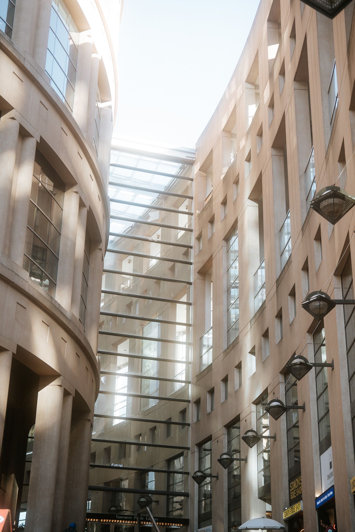 Modern architectural interior with soaring wooden beams and glass ceiling creating dramatic angles and natural lighting.