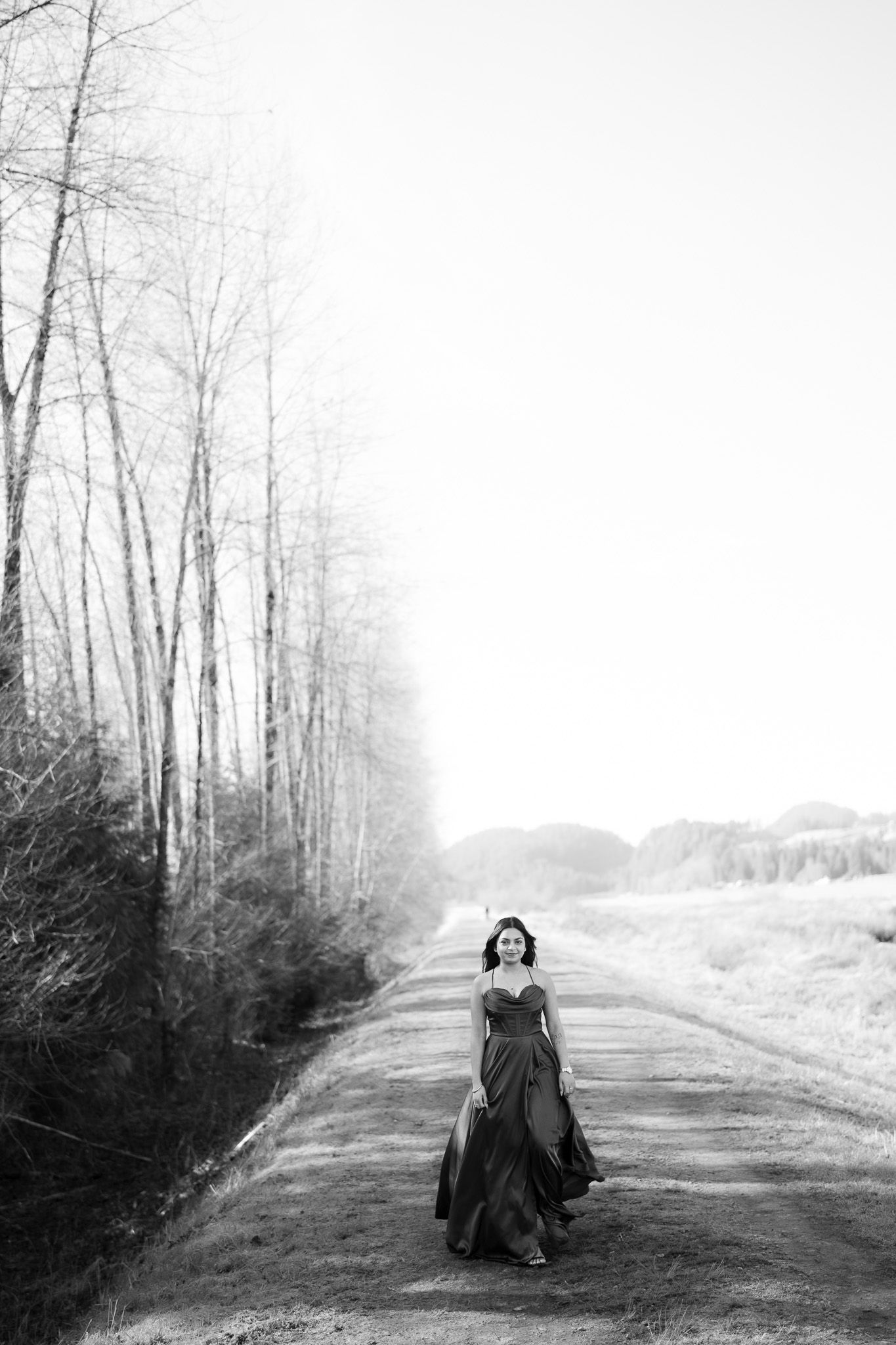 A series of four black and white photos showing a person sitting in the middle of a misty forest road.