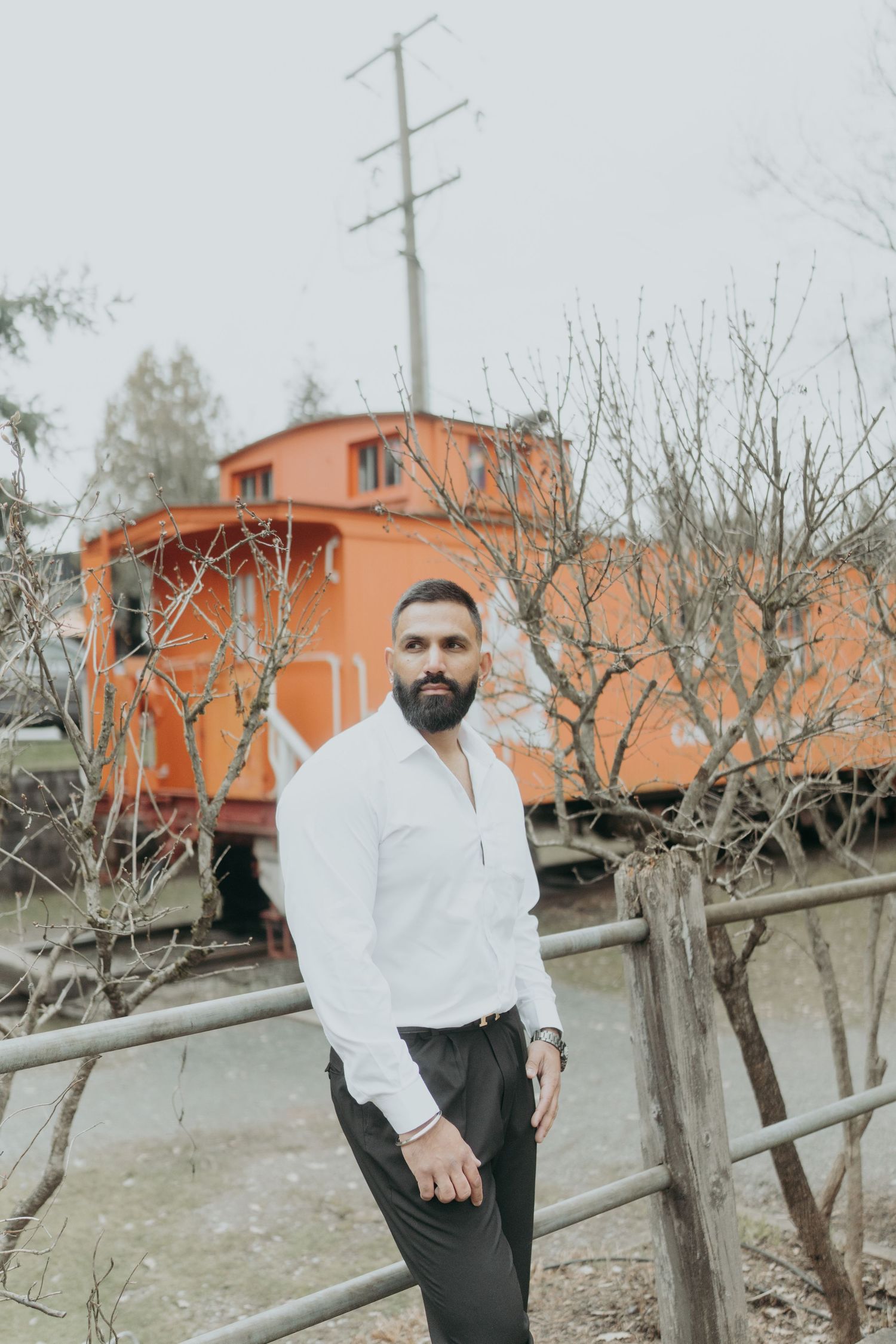 Casual portrait session featuring vintage orange train car and winter landscape.