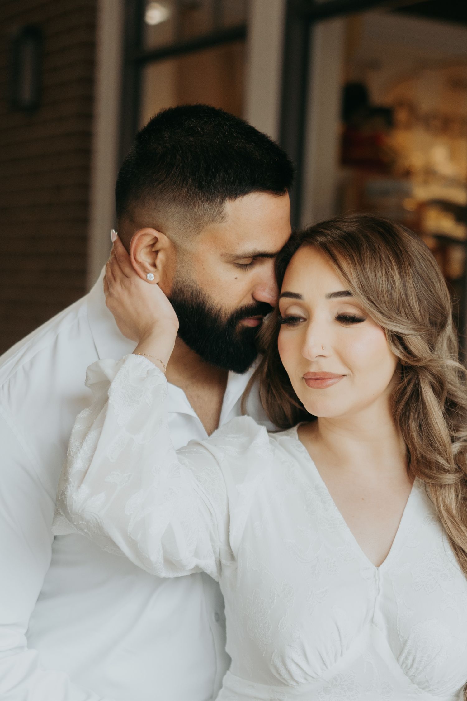 A romantic couple in white clothing shares an intimate close-up moment.