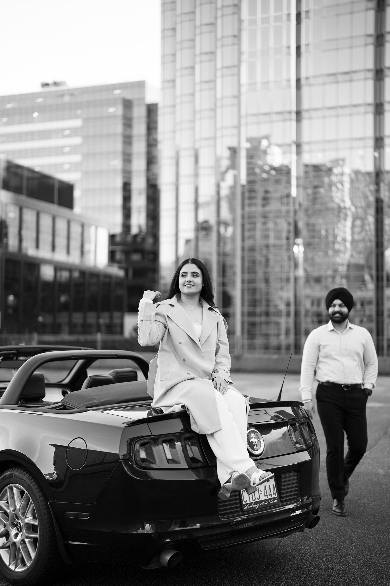 A black and white photo series showing a luxury car with people posing beside it in an urban setting.