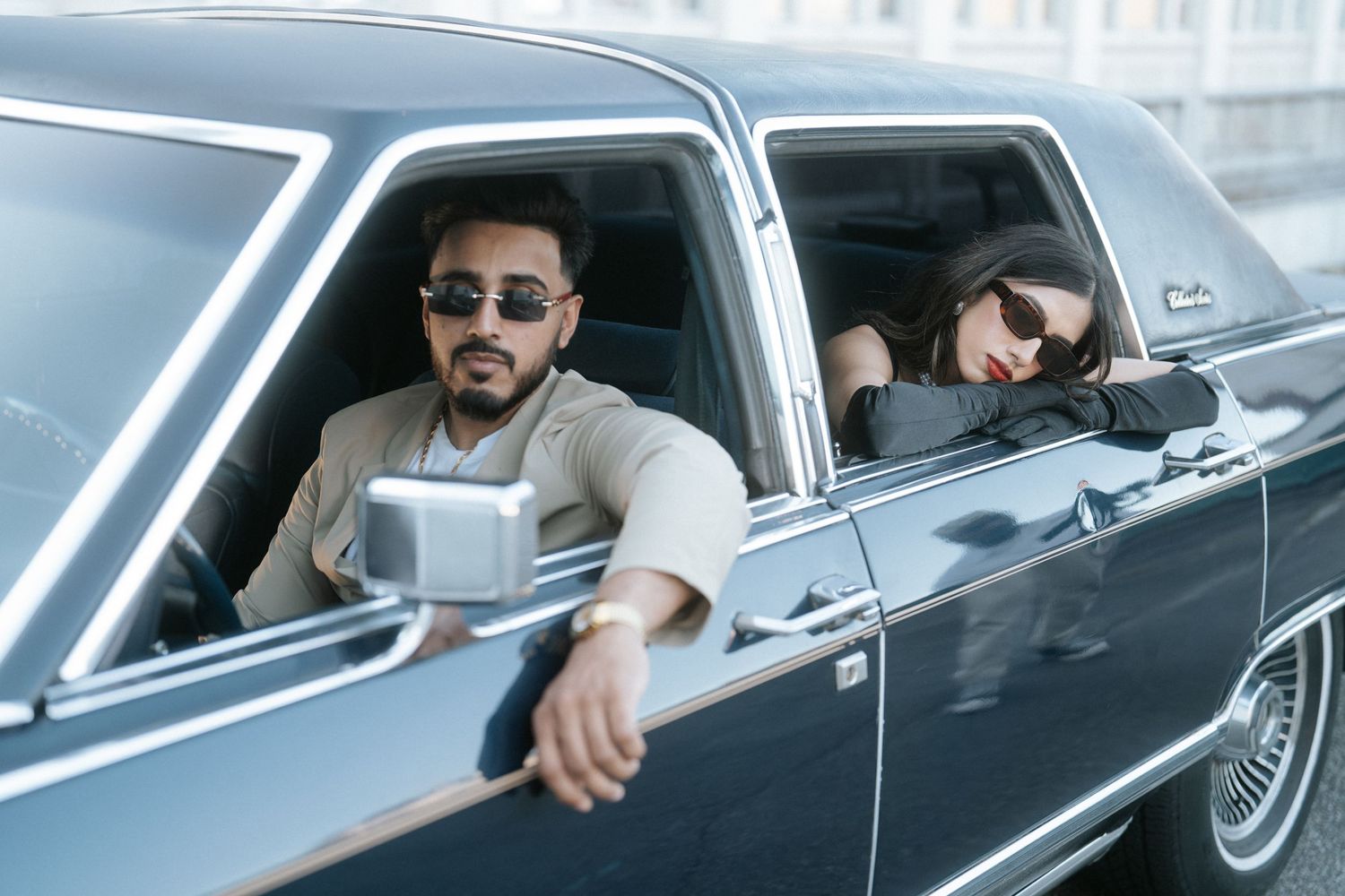 A vintage black car shown in a series of connected photos with someone sitting in the driver's seat.