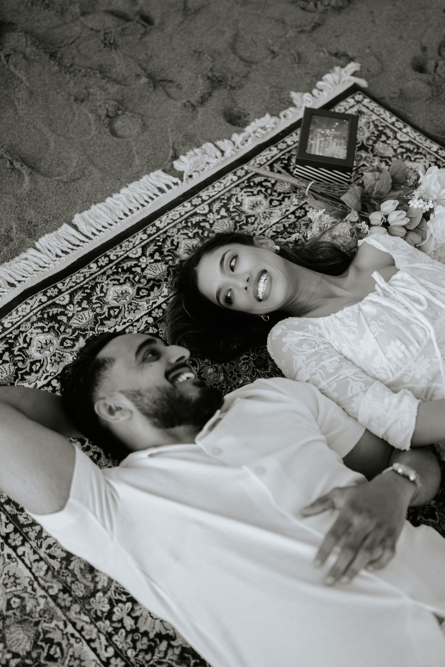 A black and white photo series shows someone lying on a patterned carpet in a white dress, captured from different angles.
