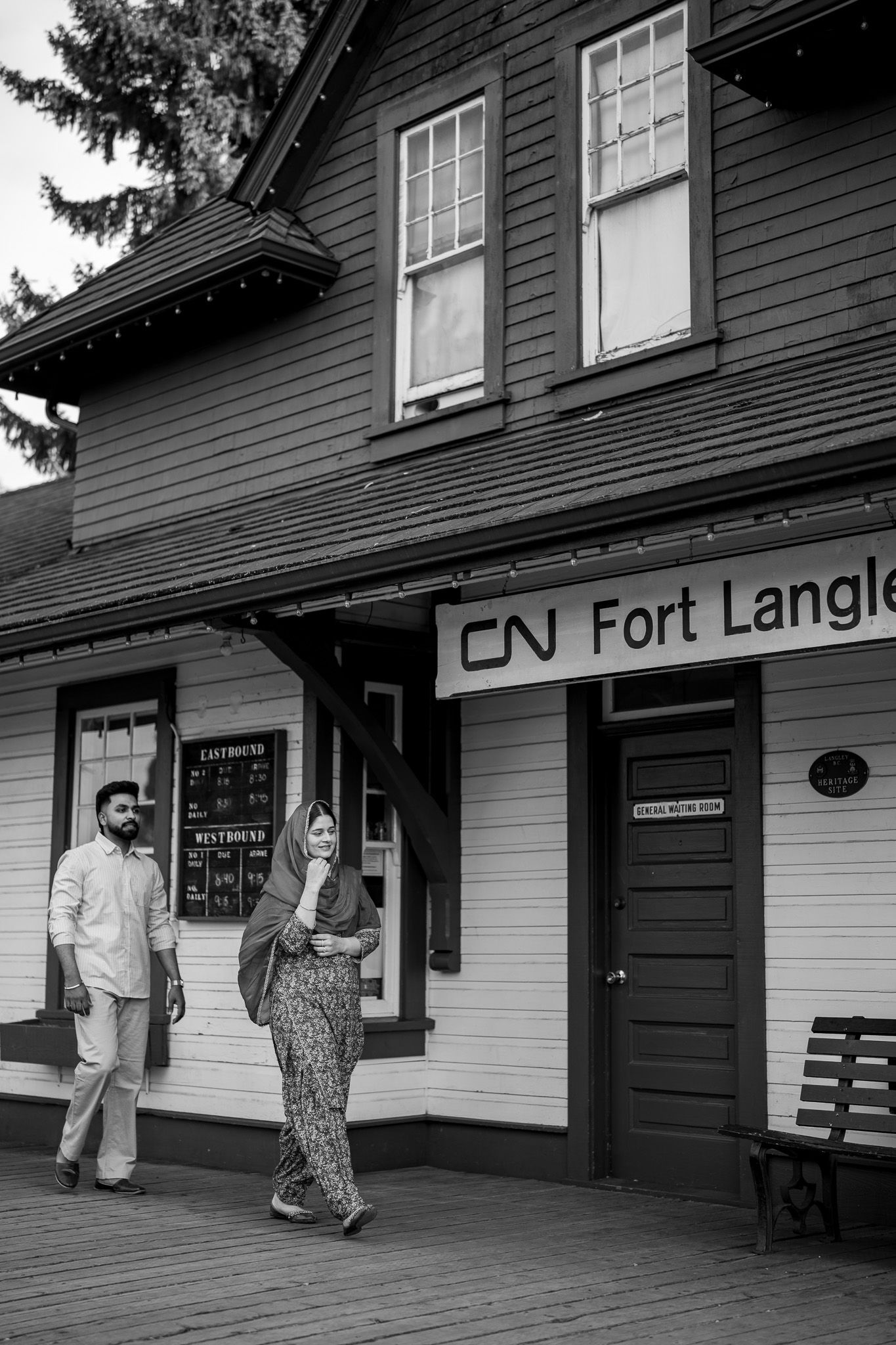 Couple walking past CN Fort Langley historic train station in black and white photography.