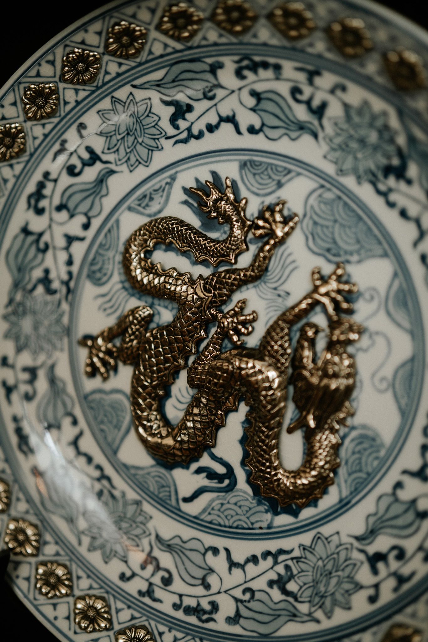 Antique Chinese blue and white porcelain plate with a raised gold dragon figurine centerpiece and floral motifs.
