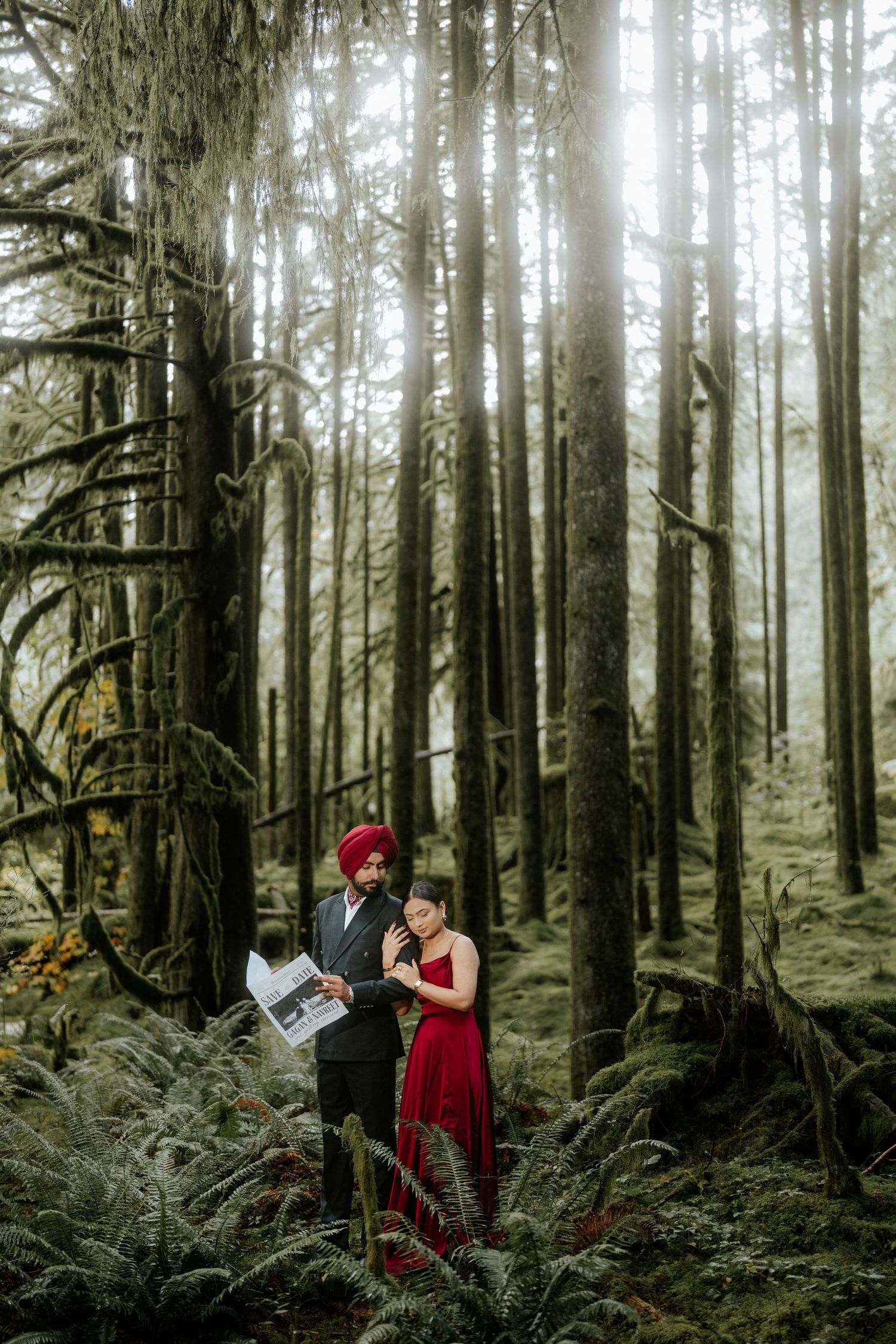 A romantic forest photoshoot featuring a red dress against mossy trees and ferns.