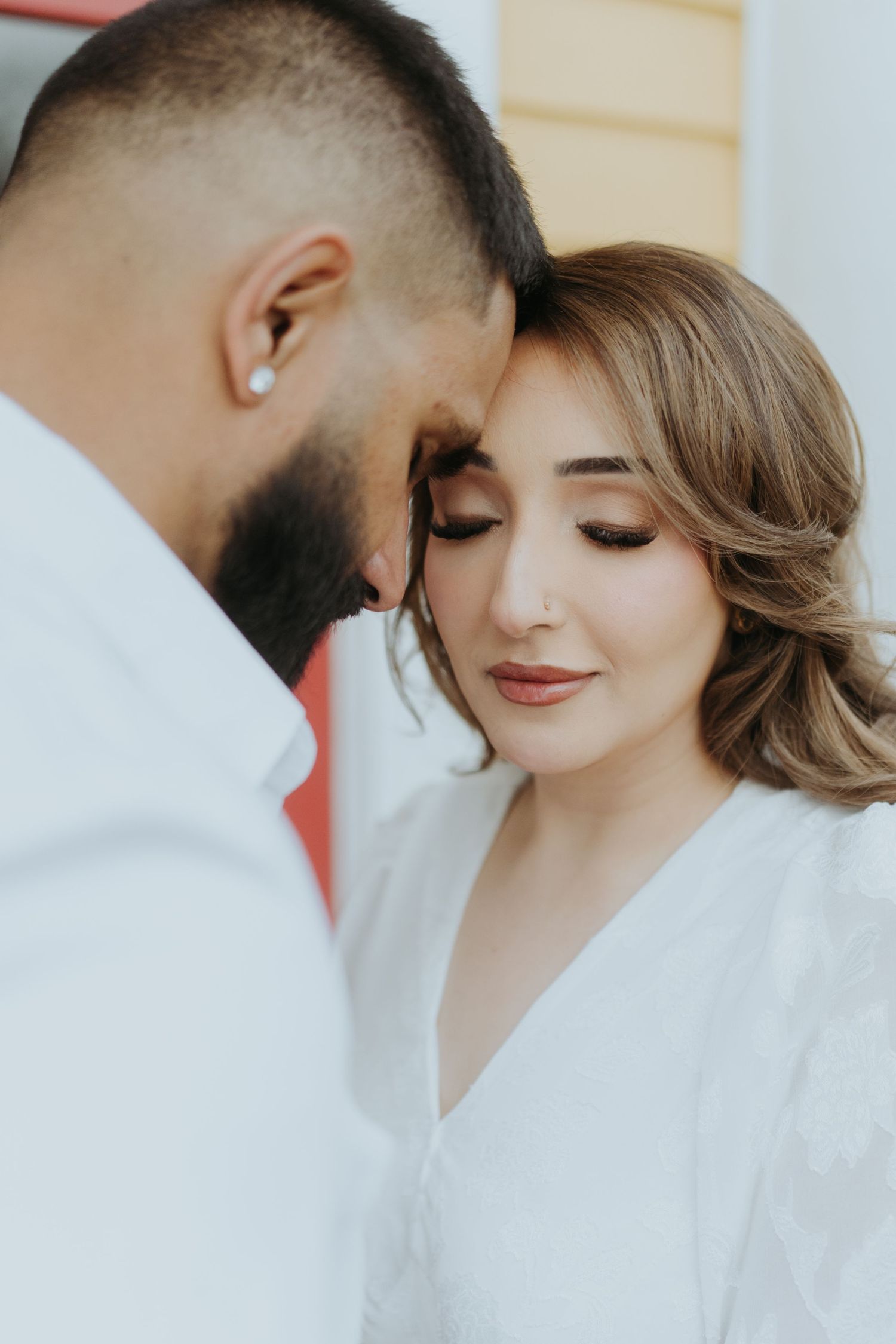 Close-up of a couple in white clothing sharing tender moments together.