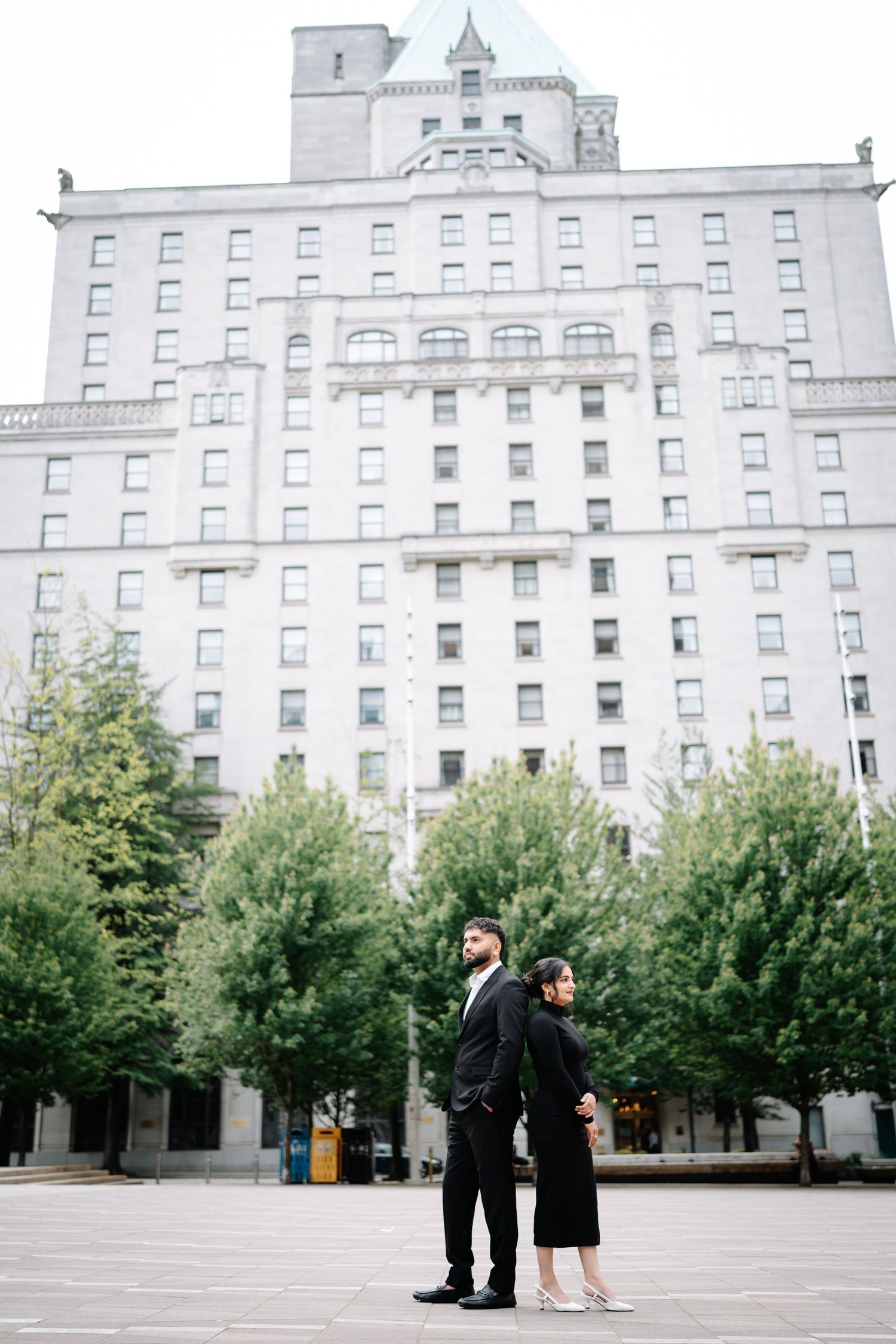 A couple poses in formal attire against a grand historic white building with trees.