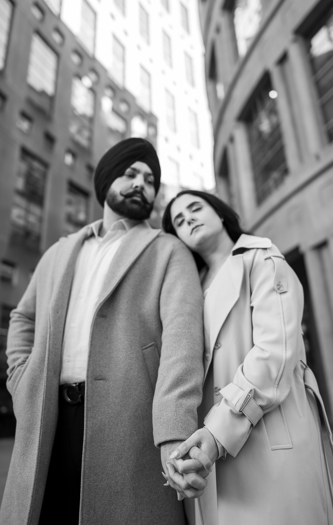 A black and white triptych showing a couple in winter coats leaning on each other in an urban setting.