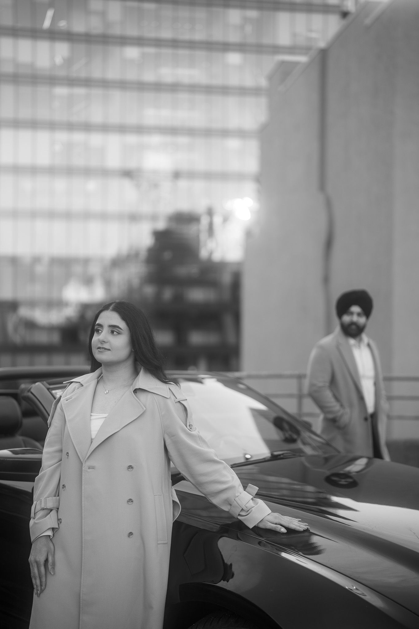 A sequence of four black and white photographs showing a person in a light-colored coat standing next to parked cars.