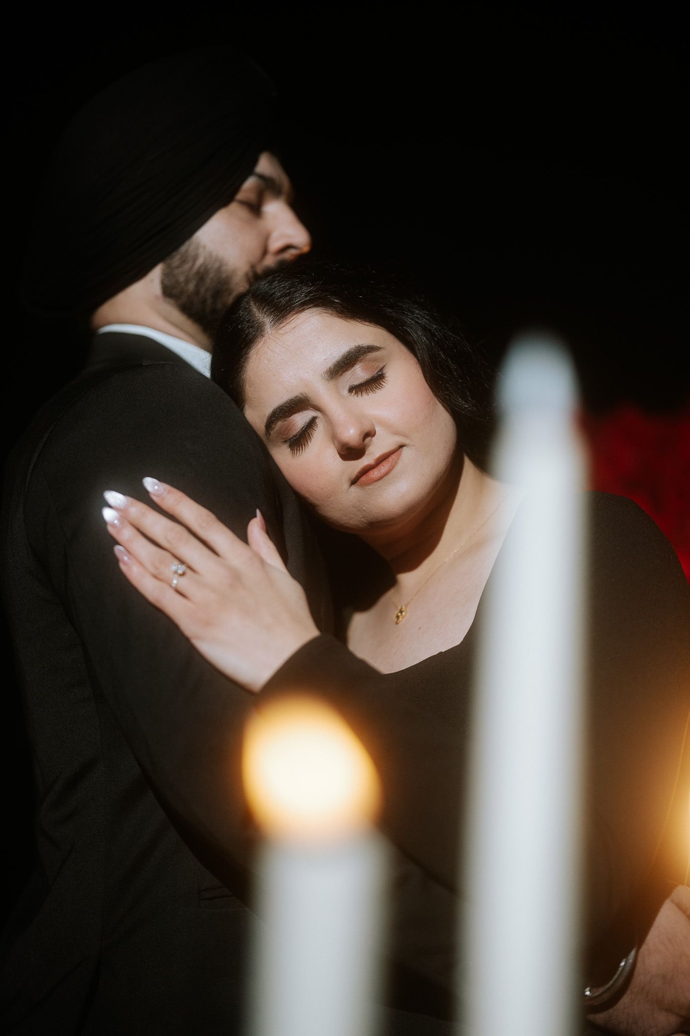 Romantic couple embraces in dramatic lighting with white beams and dark shadows creating an intimate atmosphere.