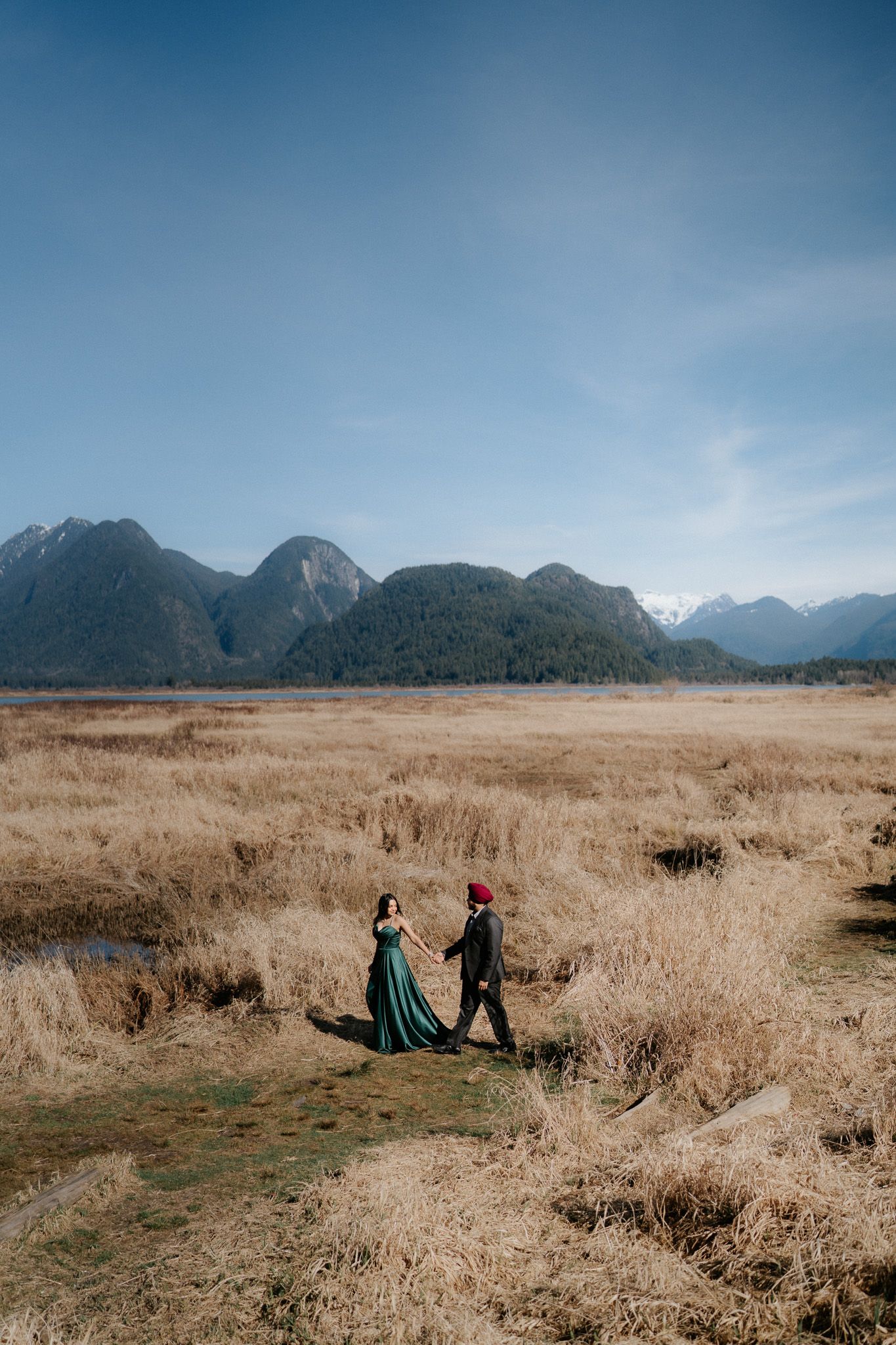 A scenic mountain landscape with golden grass fields stretches beneath a blue sky.