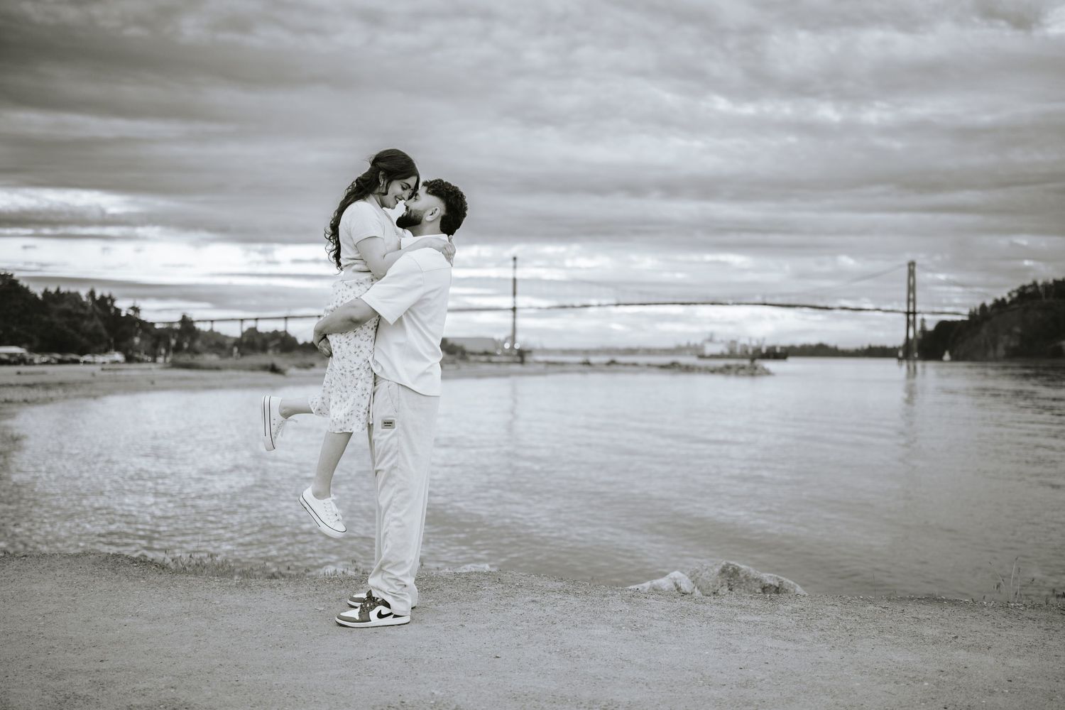 A black and white photo of a couple embracing on a misty beach.