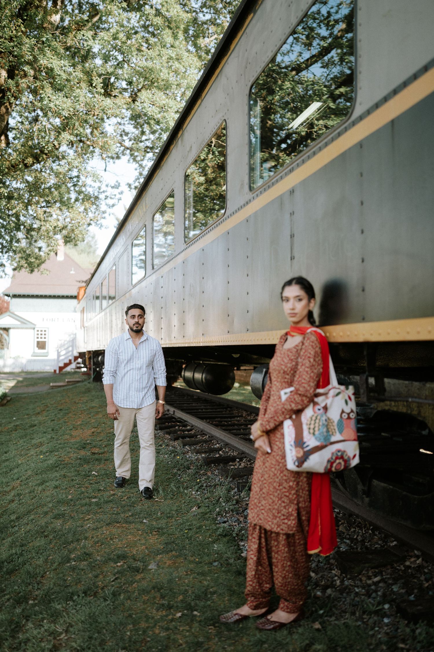 A couple poses under a rustic bridge structure during an outdoor photoshoot at sunset.