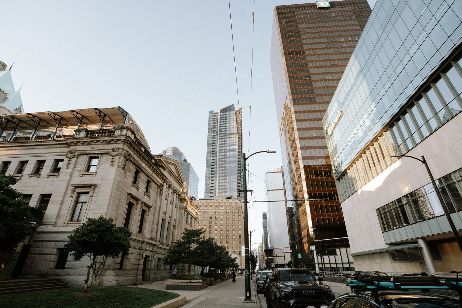 Modern glass skyscrapers tower over historic architecture in downtown Vancouver's financial district.