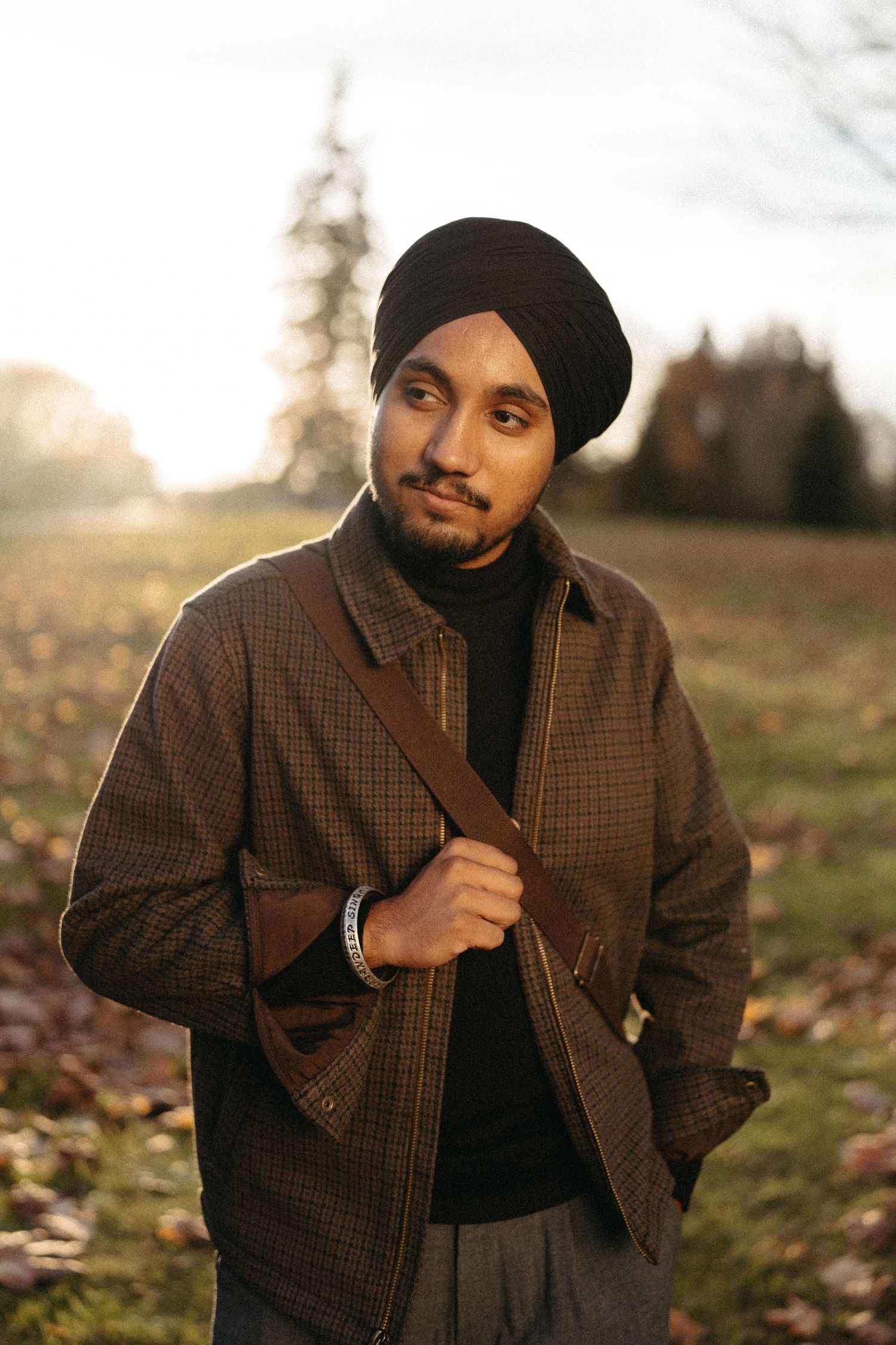Person in brown plaid jacket and black beanie poses outdoors during autumn.