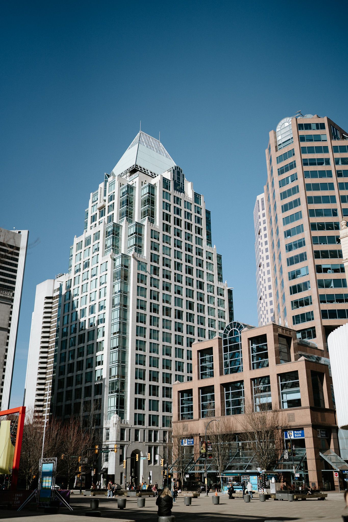 Modern white office buildings with glass facades stand tall against a blue sky in an urban business district.