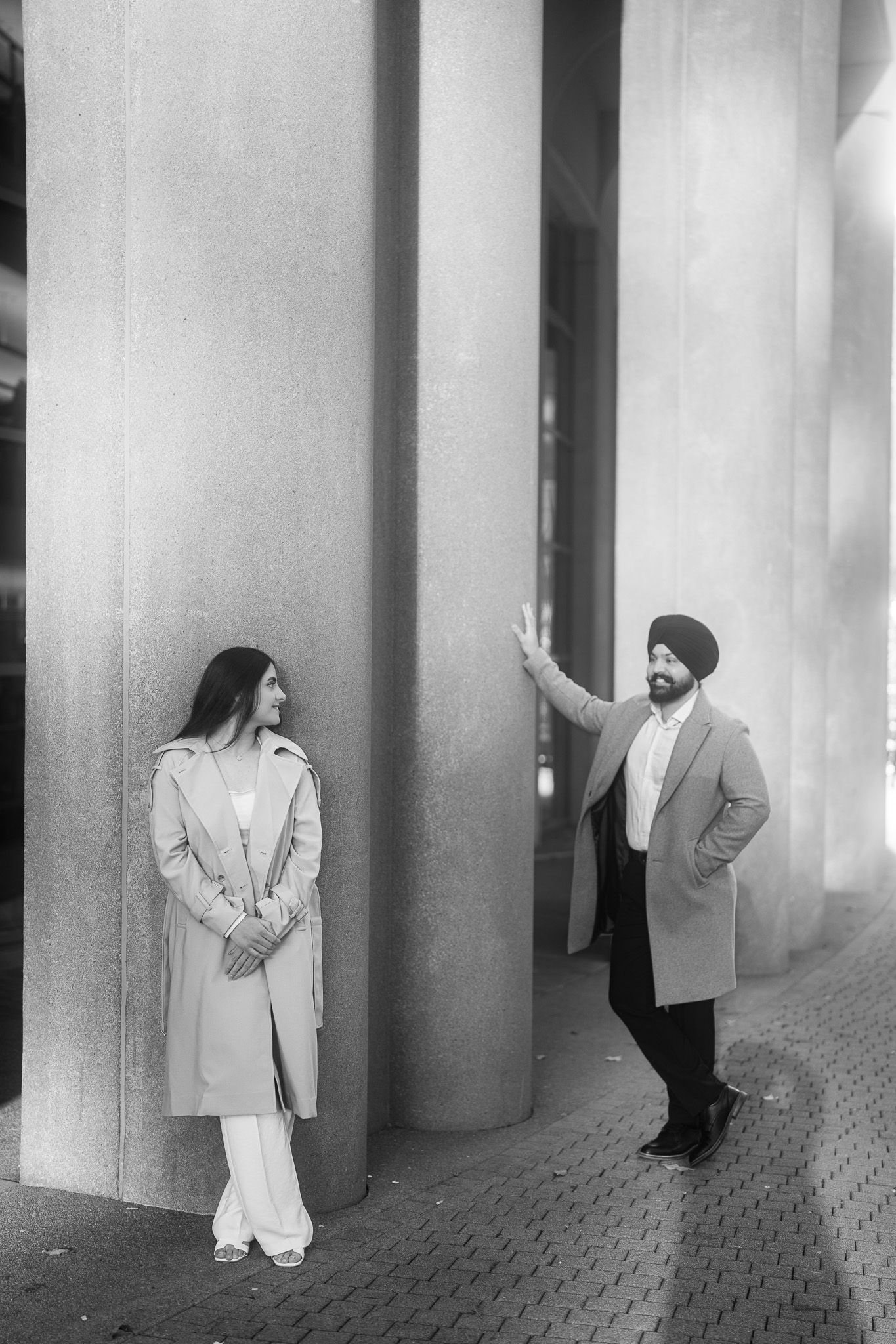 A series of black and white photos showing figures standing between tall columns in a minimalist architectural space.