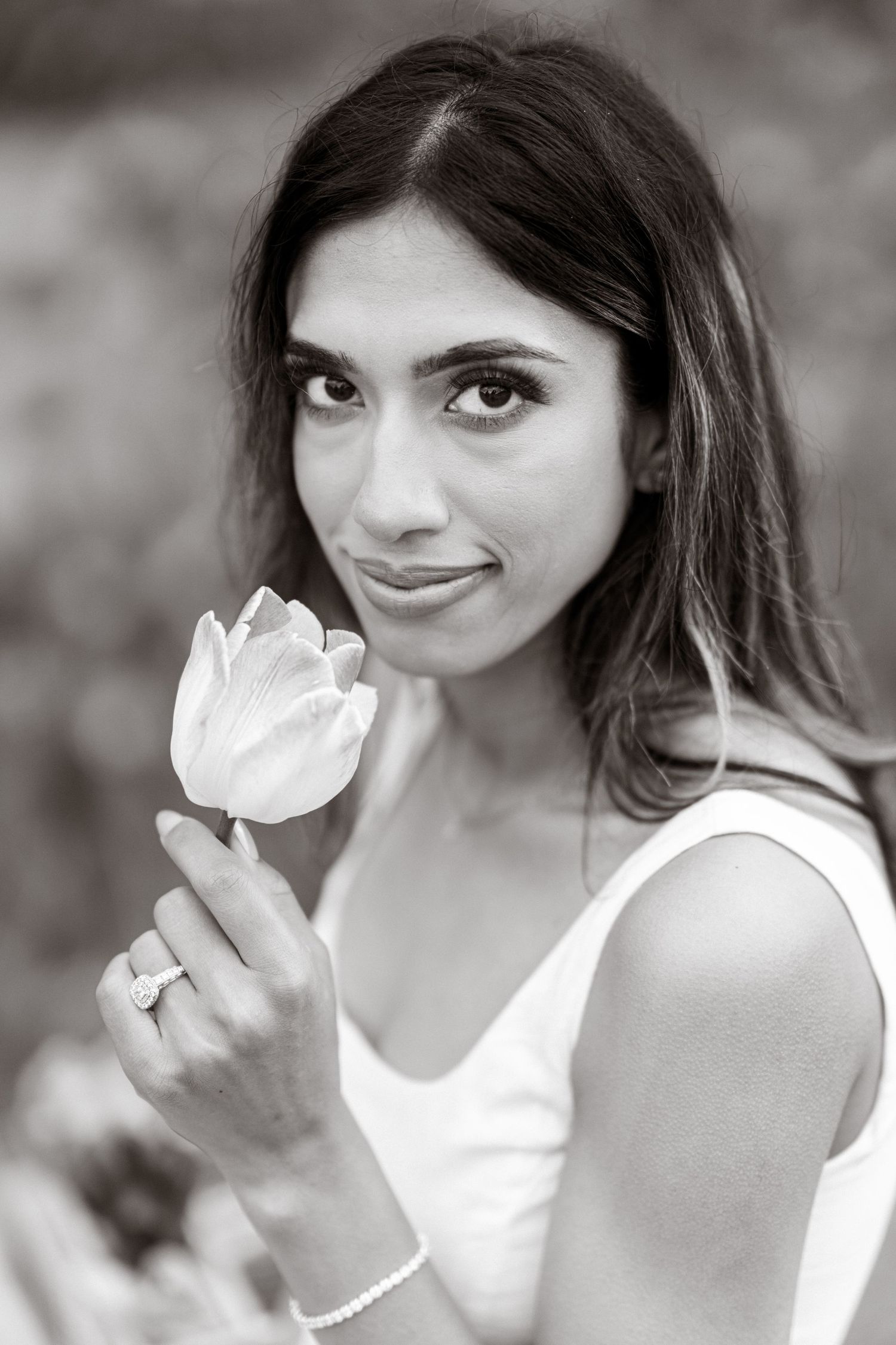 A black and white portrait series showing a person in a white top holding a delicate white flower.