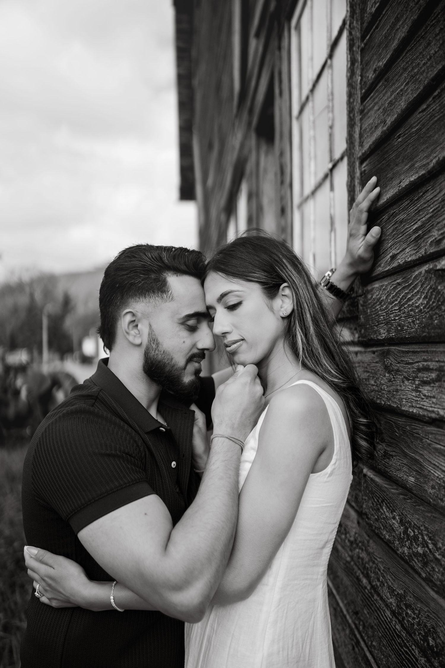 A romantic black and white photo series shows a couple sharing intimate moments against a rustic wooden wall.