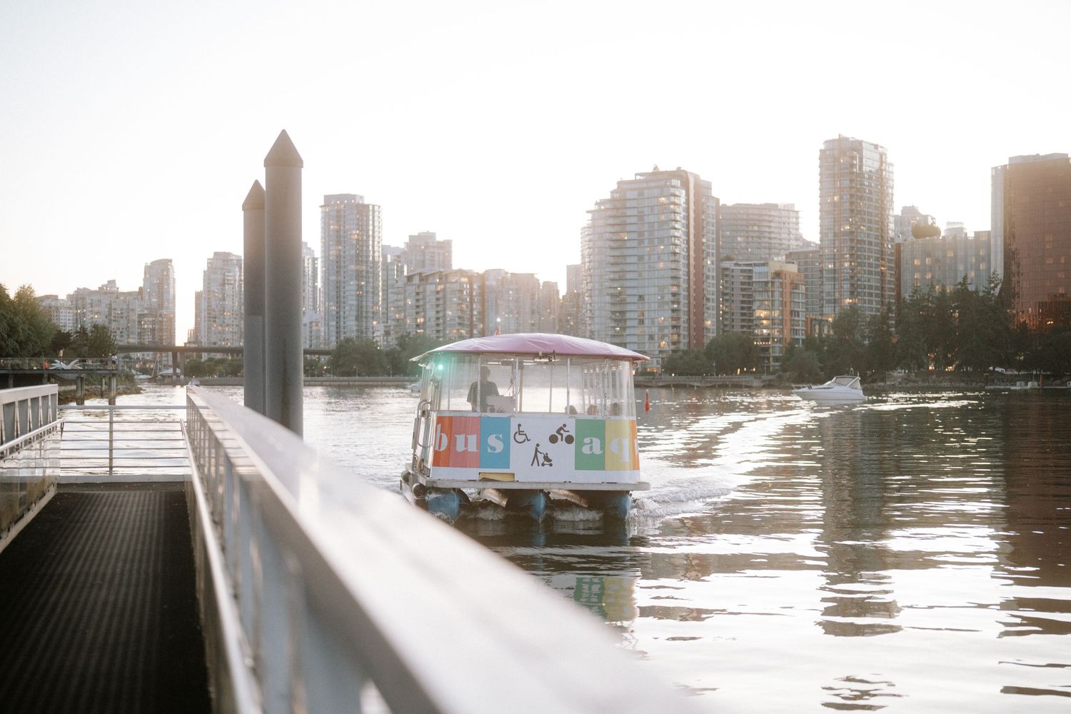 Scenic urban waterfront view of buildings and boats along a river during sunset with warm golden lighting.