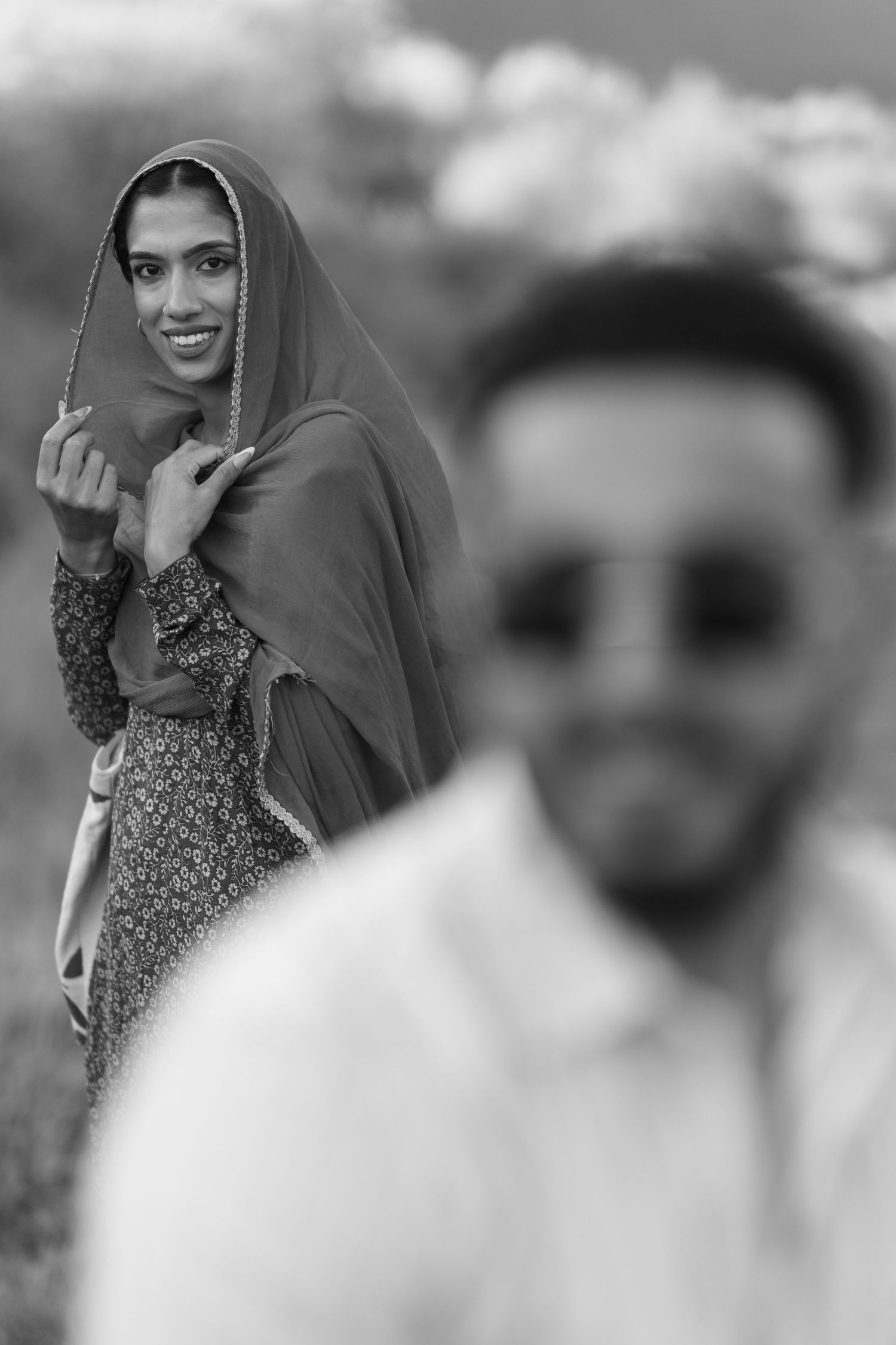 A series of black and white fashion portraits showing someone wearing a floral dress and headscarf in different poses.