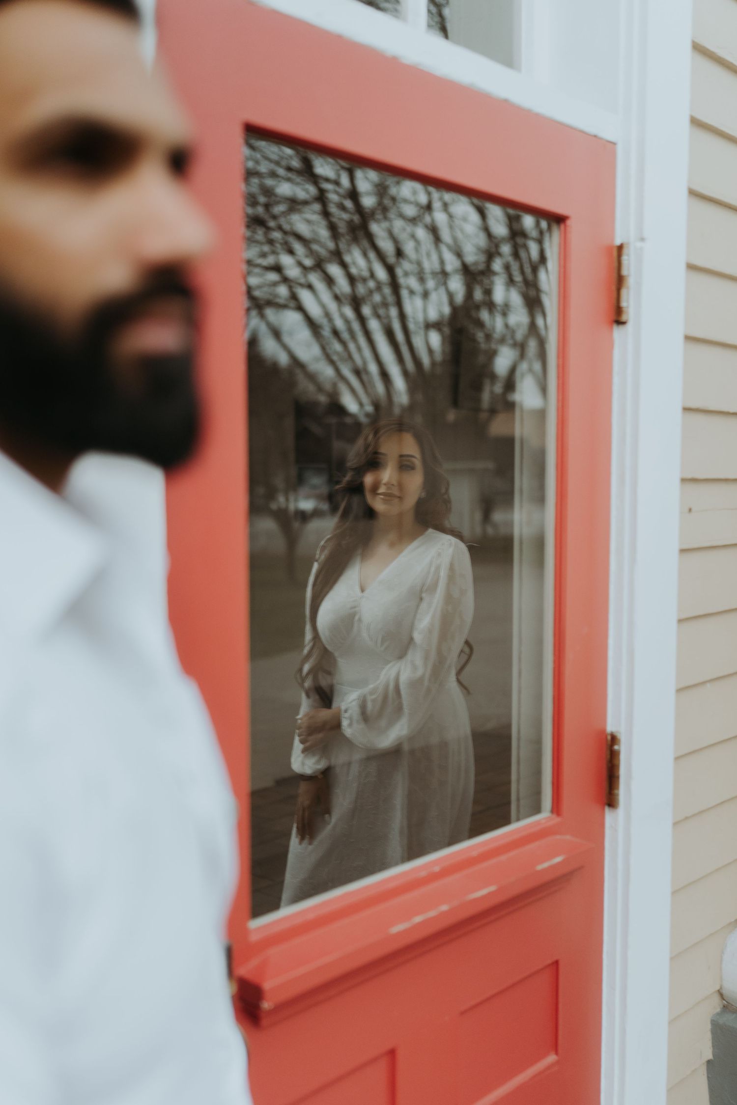 Red door with glass panel detail against white and yellow building exterior.