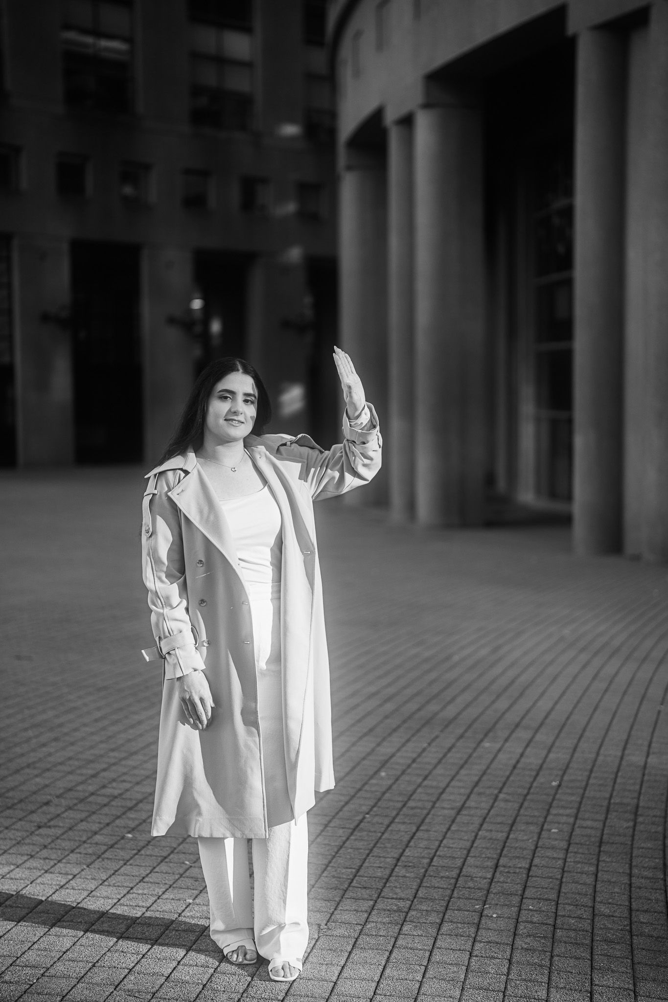 A series of black and white photos showing a person in a white coat posing on a tiled outdoor walkway.