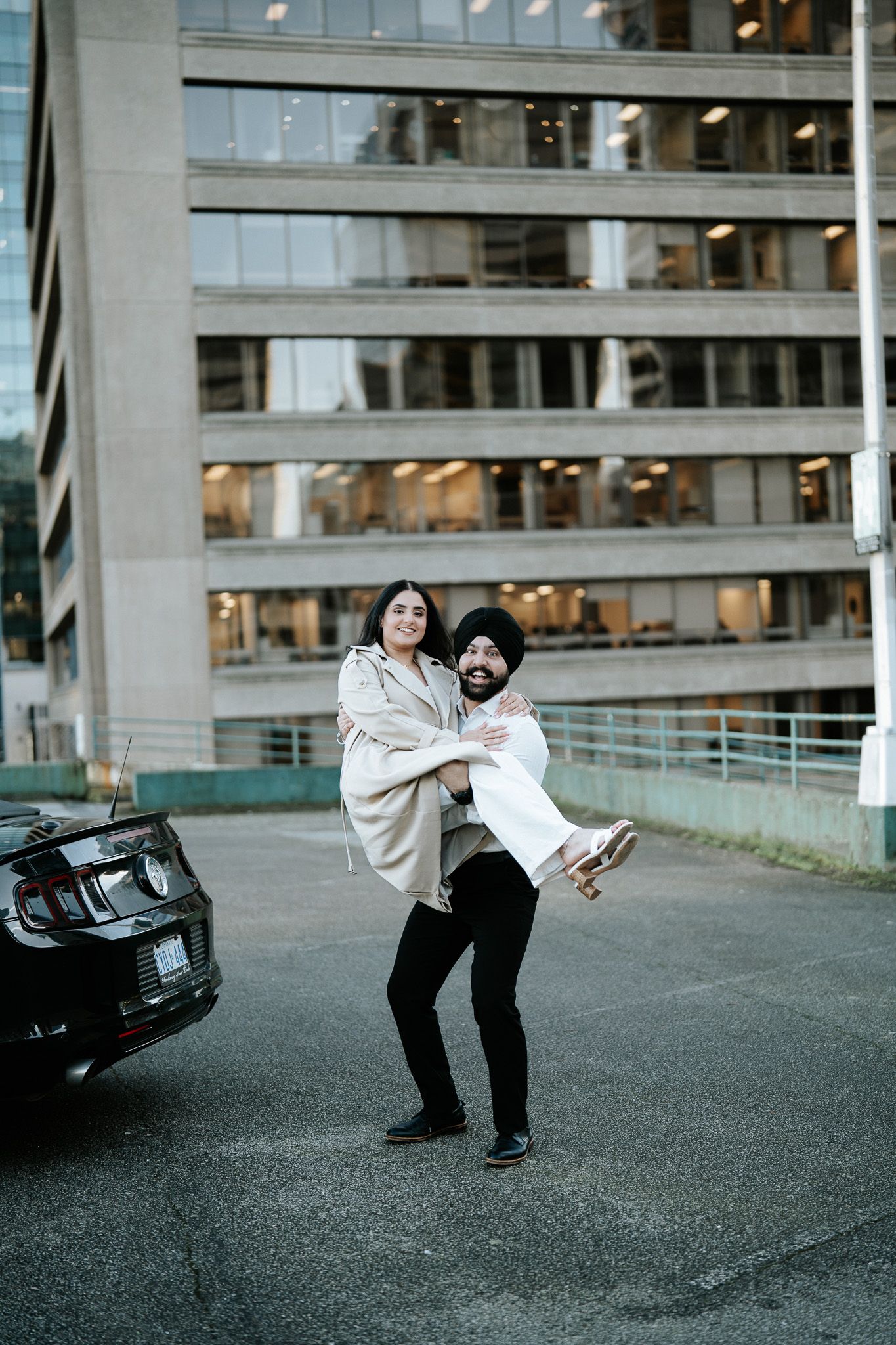A couple performs a playful dance dip sequence on an urban street with an office building in the background.