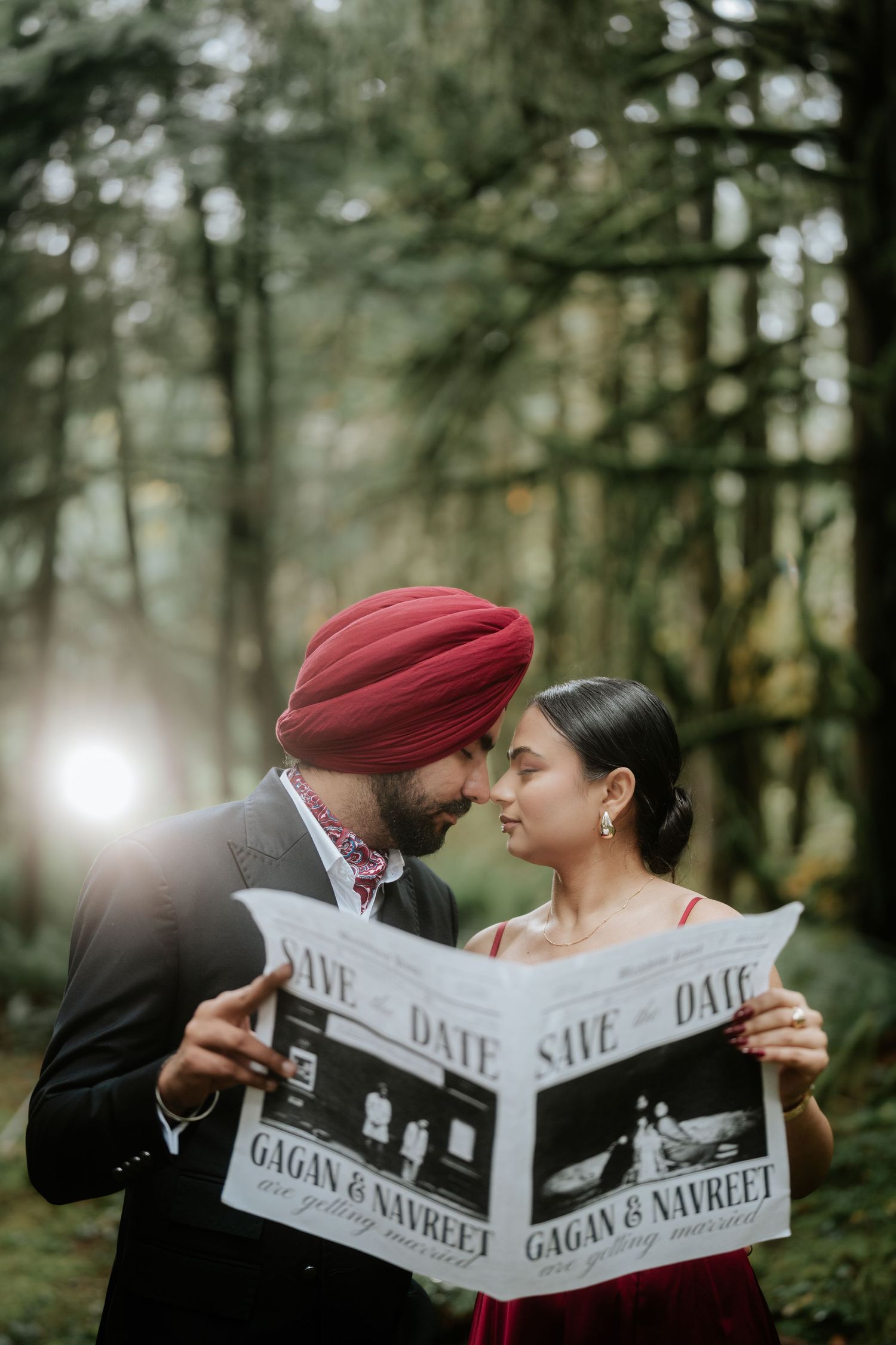 Couple reads their wedding save the date announcement together in a wooded setting.