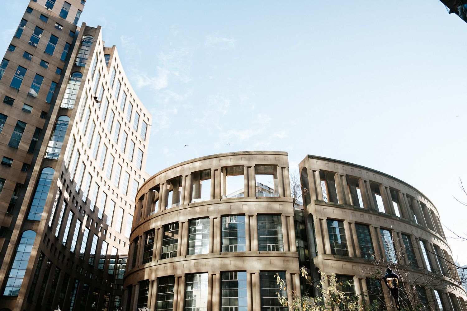 Modern curved glass office building facade with rounded architectural features in an urban setting.