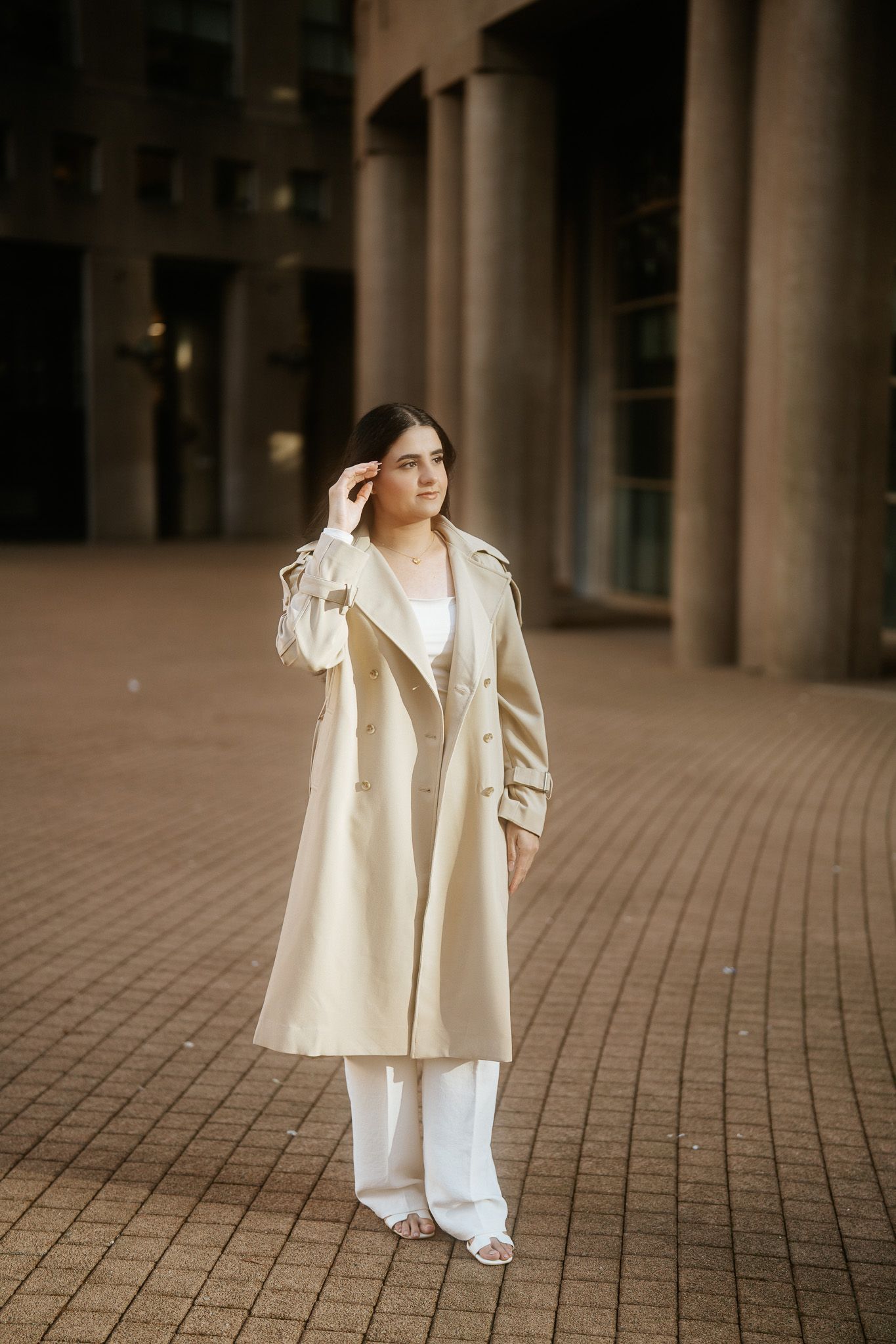 A series of fashion photos showing a person in a flowing cream-colored coat and white pants against a stone-tiled backdrop.