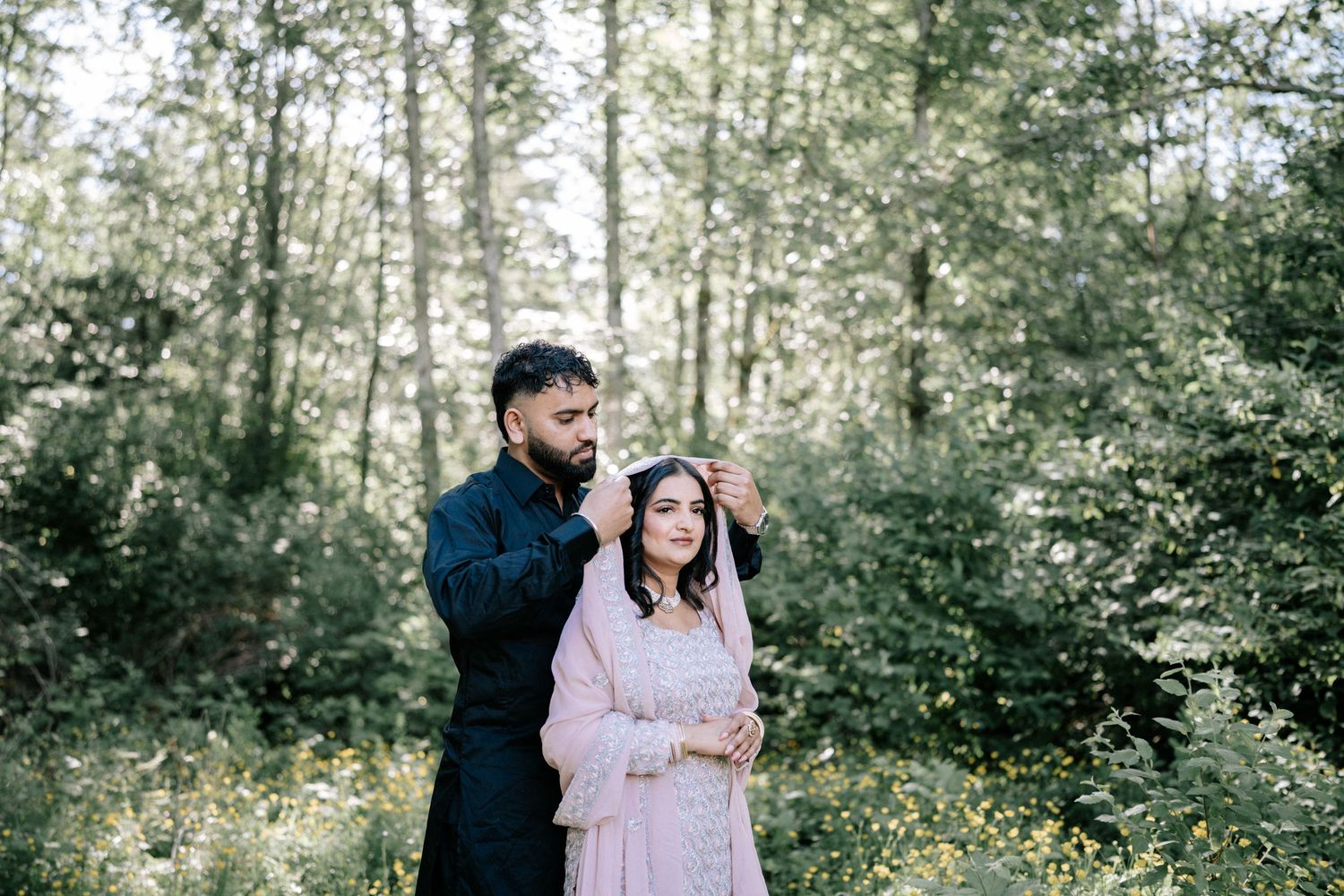 A romantic photoshoot in a lush forest setting with soft natural lighting.