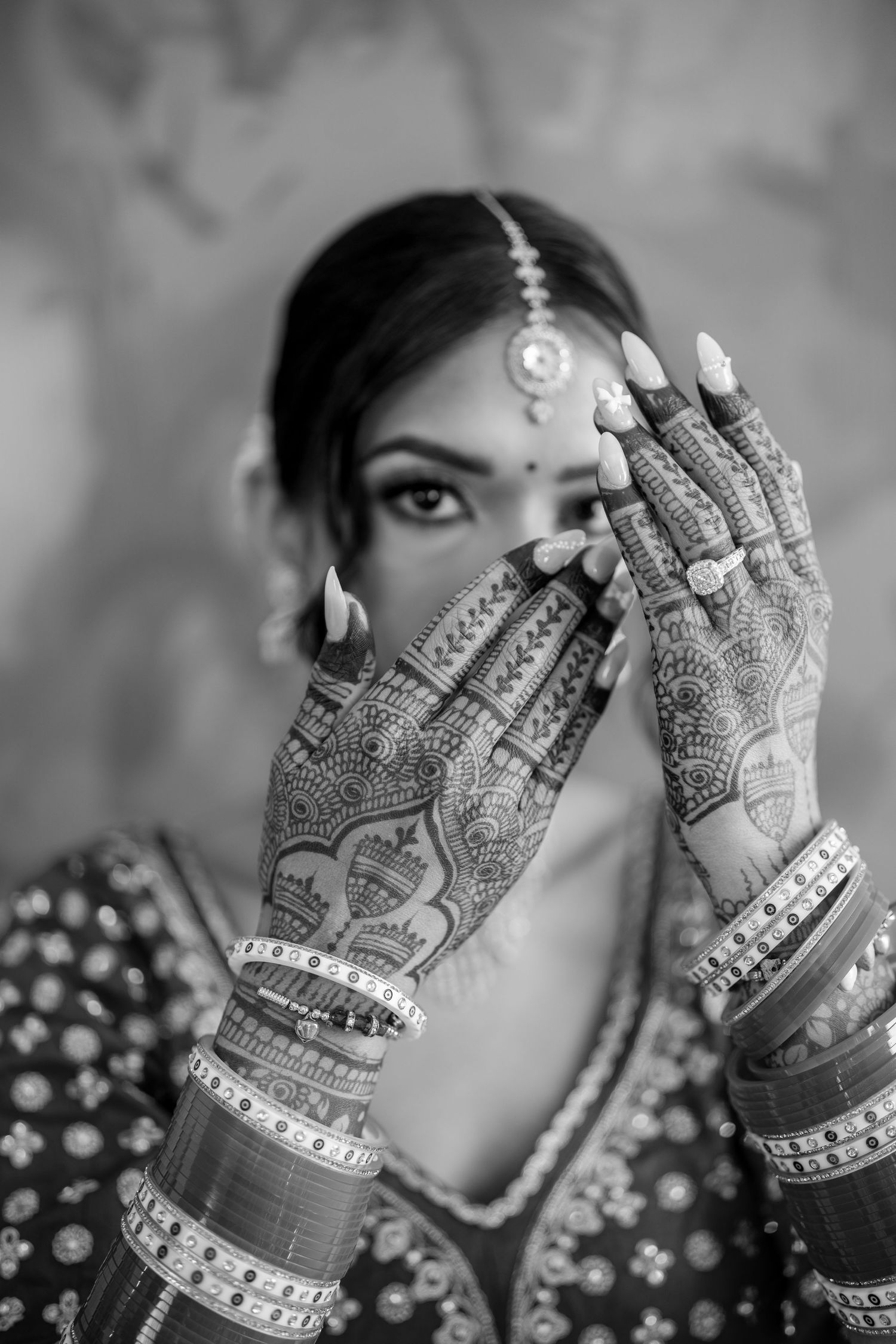 Black and white photo series showing detailed mehndi designs on hands adorned with bangles.