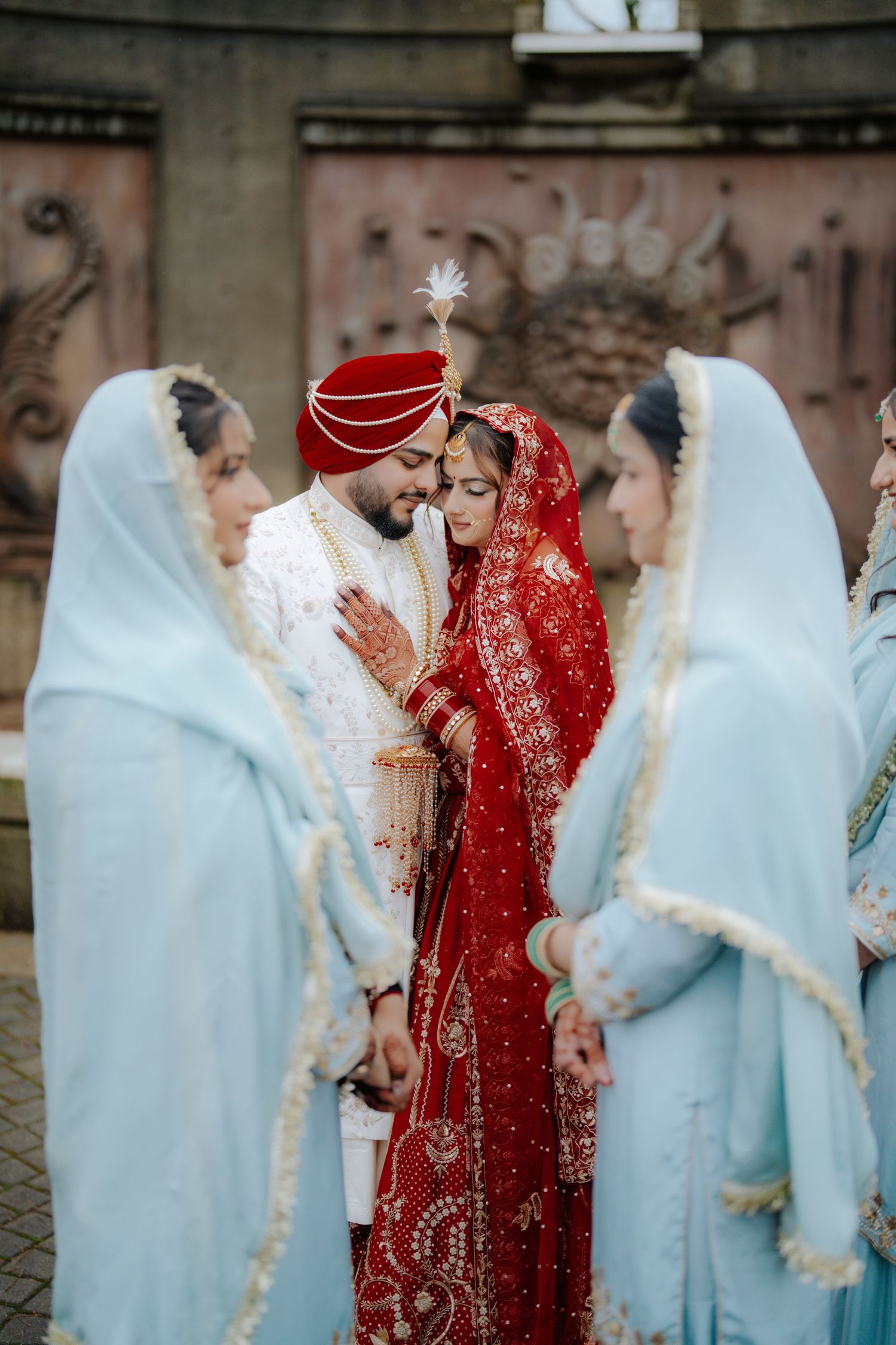 Wedding party in traditional attire with bridesmaids in light blue and couple in red and white.