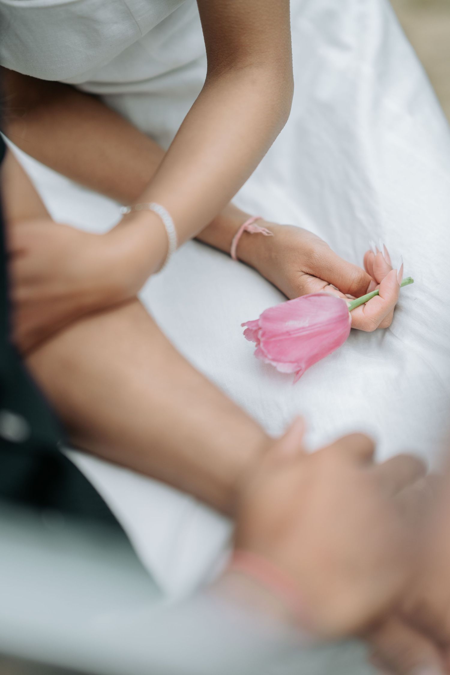A series of images showing hands gently folding and manipulating pink tissue paper against a white surface.