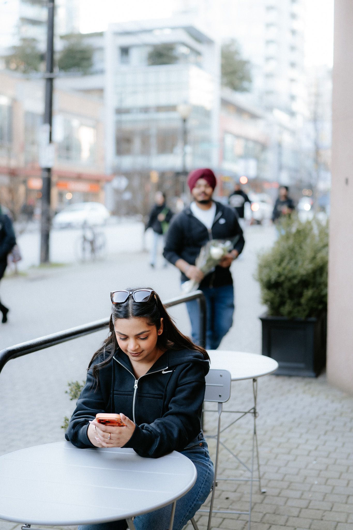 People enjoying coffee at outdoor cafe tables on a paved patio area.