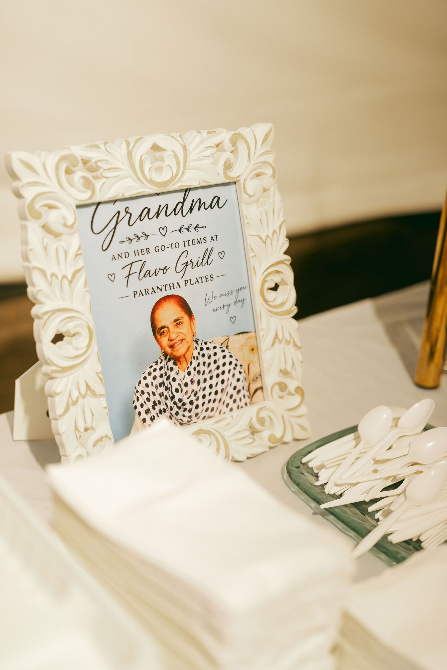 Framed photo of grandma displayed at Flavo Grill food station with parantha plates sign at a wedding reception.