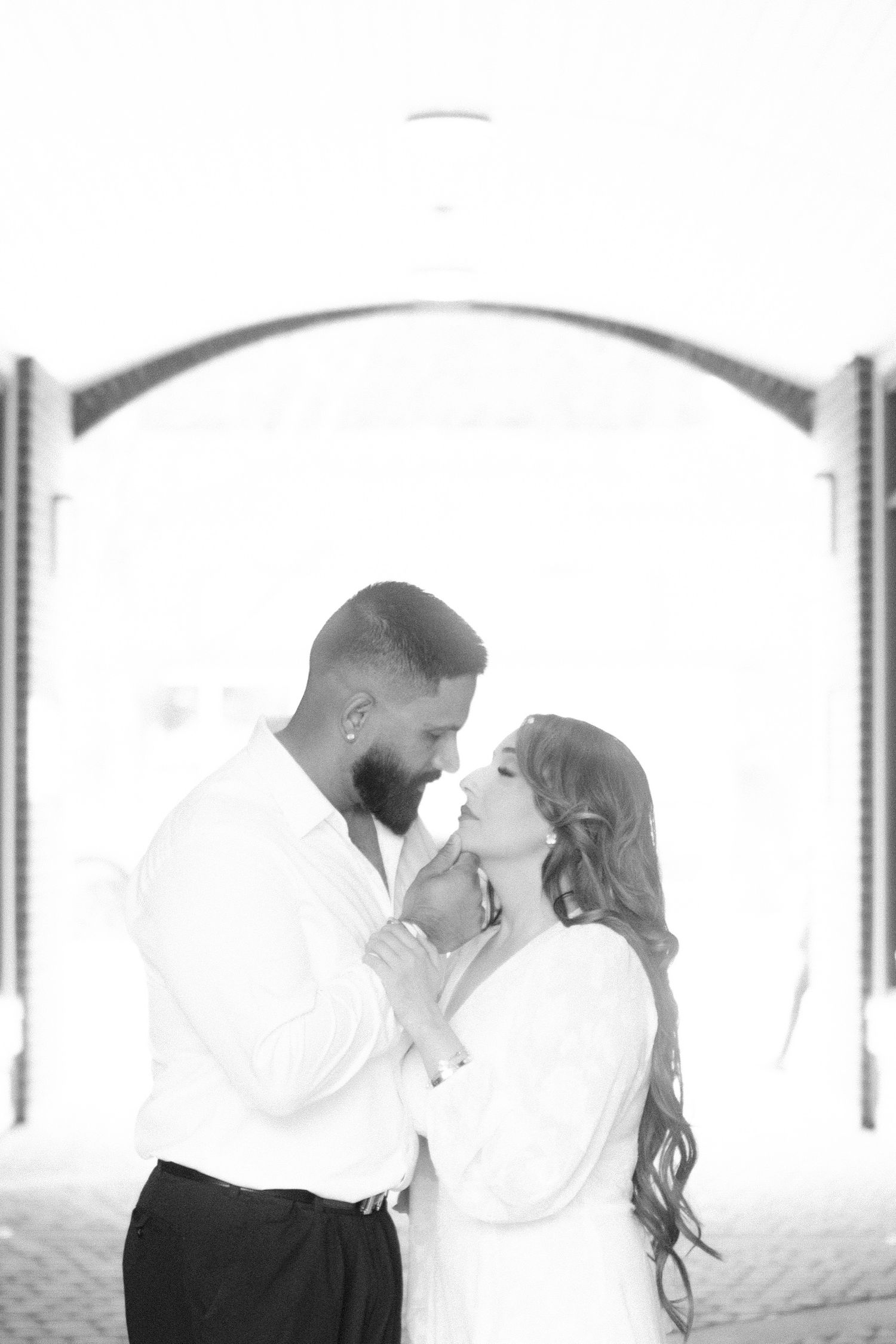 Black and white series of romantic poses in an arched architectural setting.