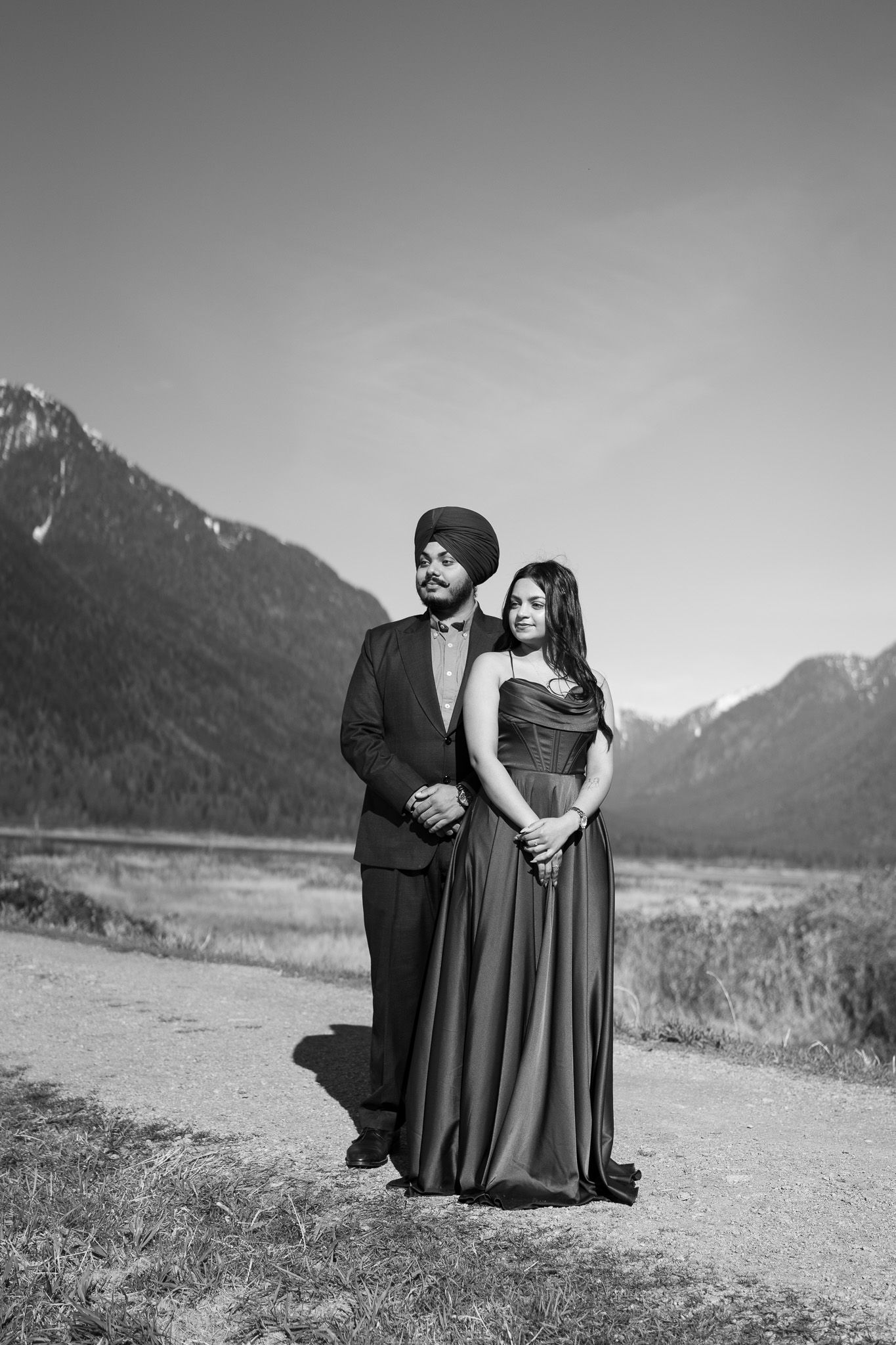 A romantic black and white photo series of a couple posing together against a mountainous landscape backdrop.
